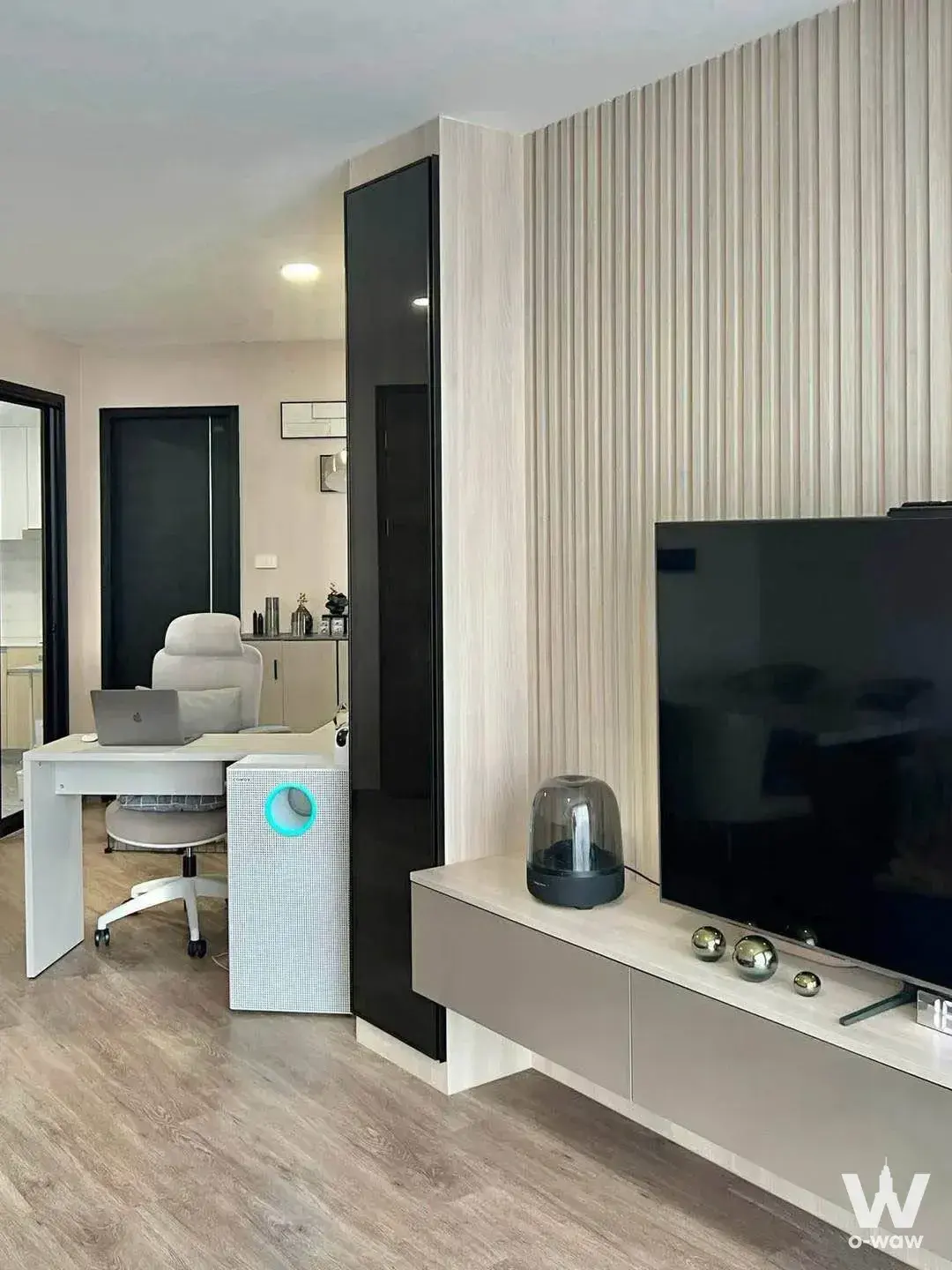 Living room and home office combo in this 2-bed Artisan Ratchada rental featuring a wood slat accent wall and L-shaped desk