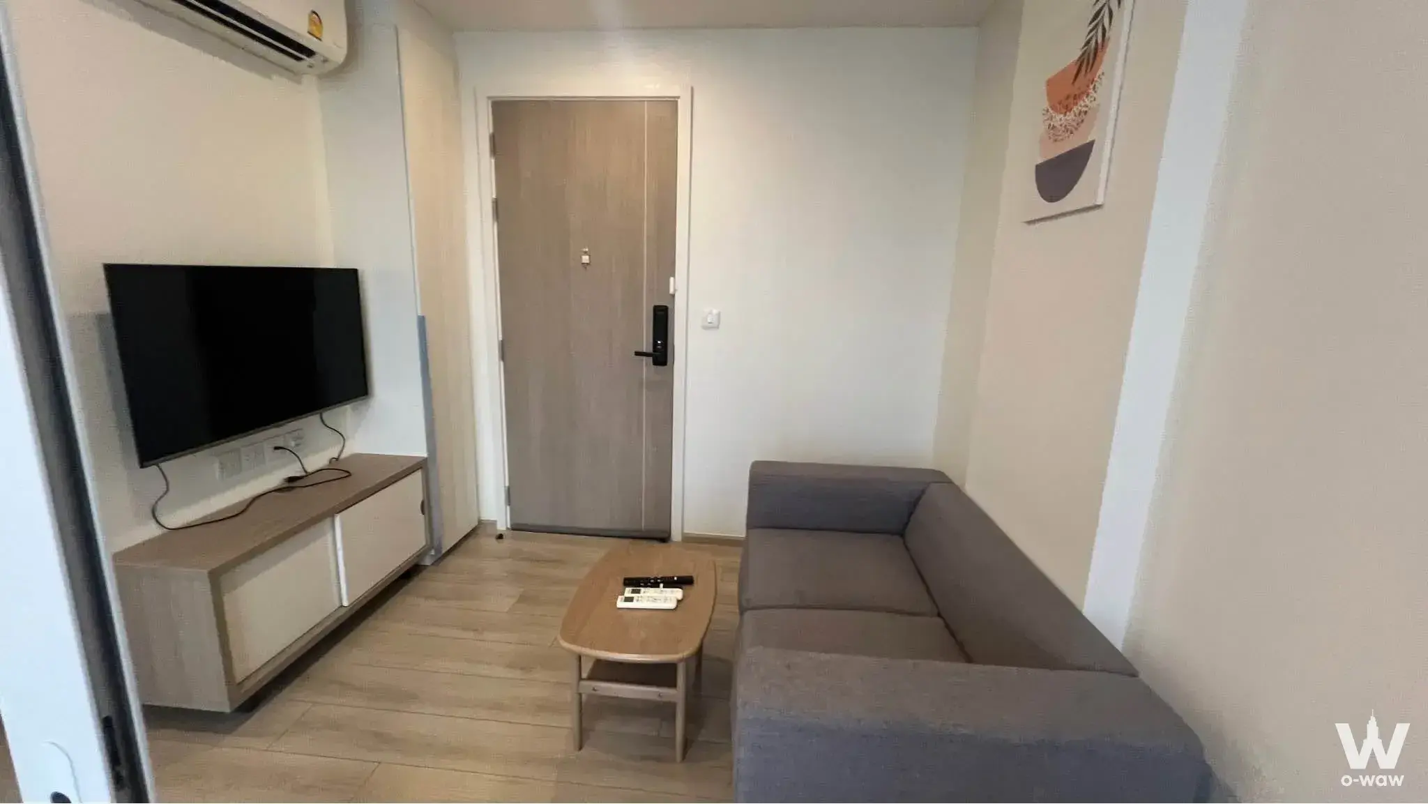 Modern 1-bed condo living space at CHAMBERS On Nut with grey sofa wood console and geometric wall art
