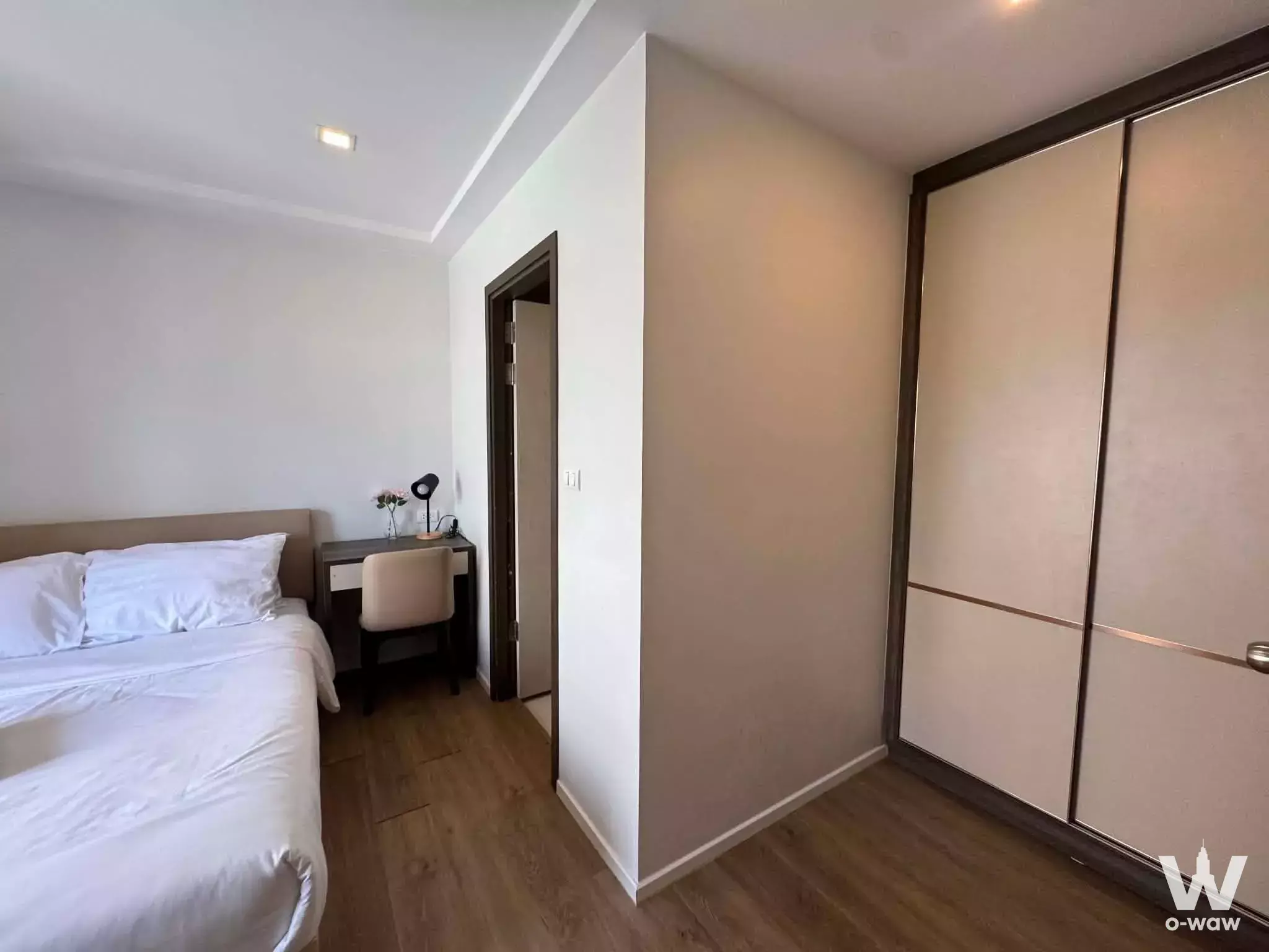 The Nest Sukhumvit 64 bedroom featuring queen bed, dark wood desk, and built-in wardrobe