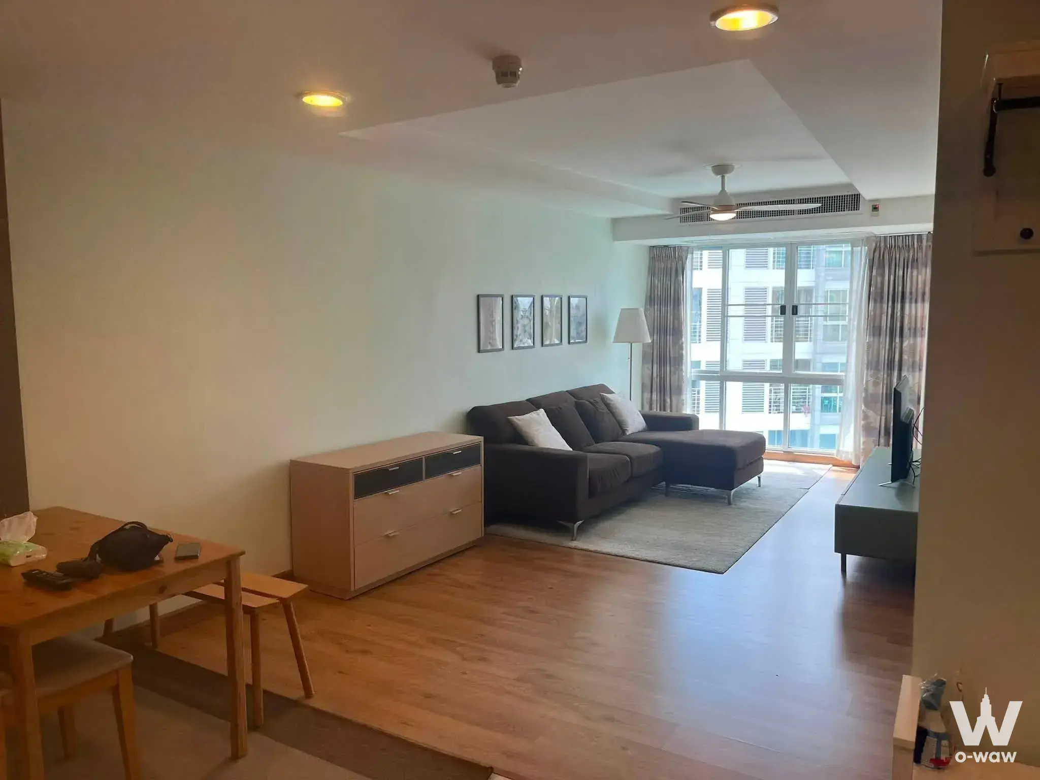 Furnished living room in Harmony Living 1-bed house rental with L-shaped sofa and balcony access