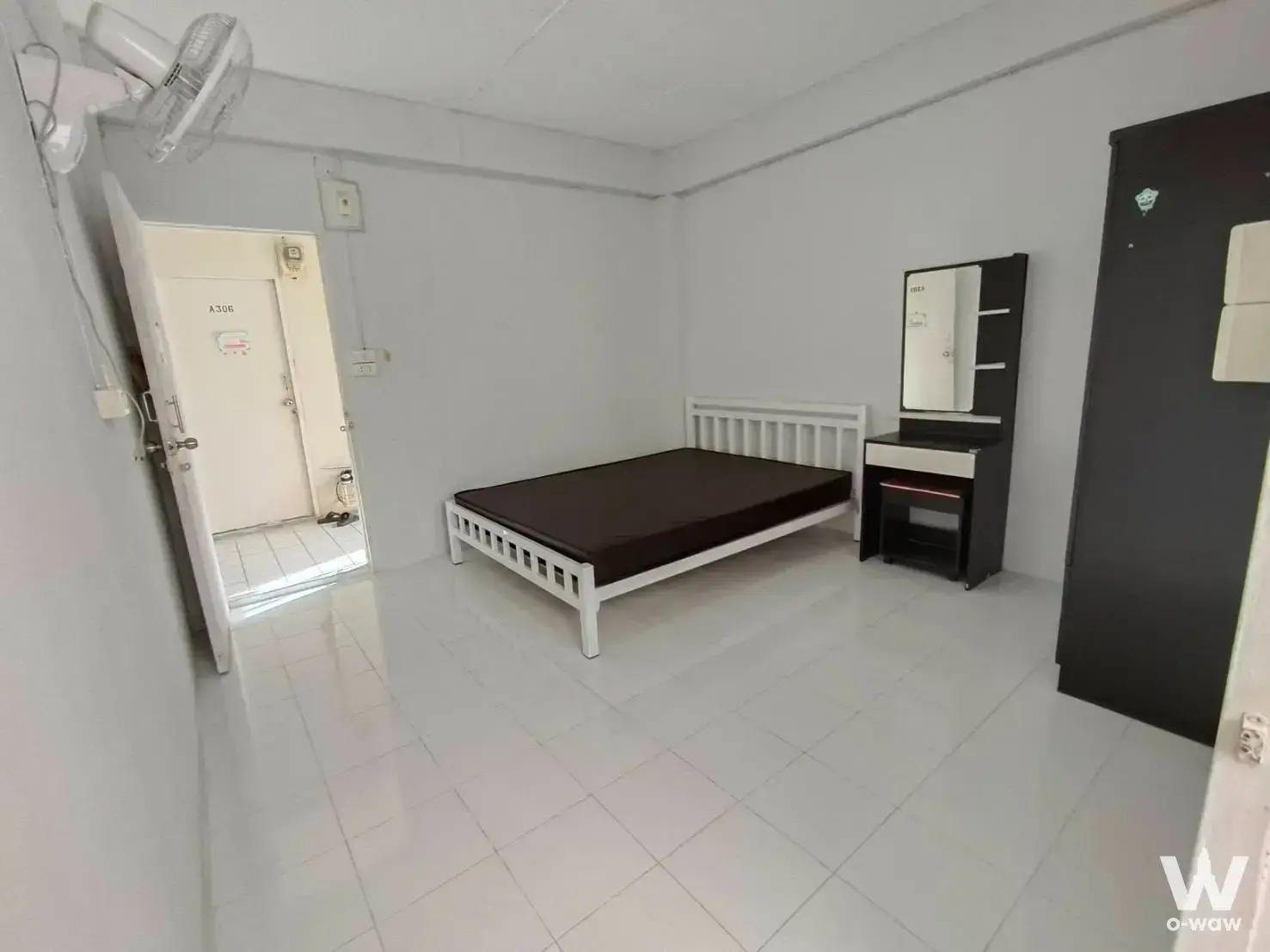 Basic studio bedroom with white walls, black wardrobe, and vanity desk at Surat Apartment