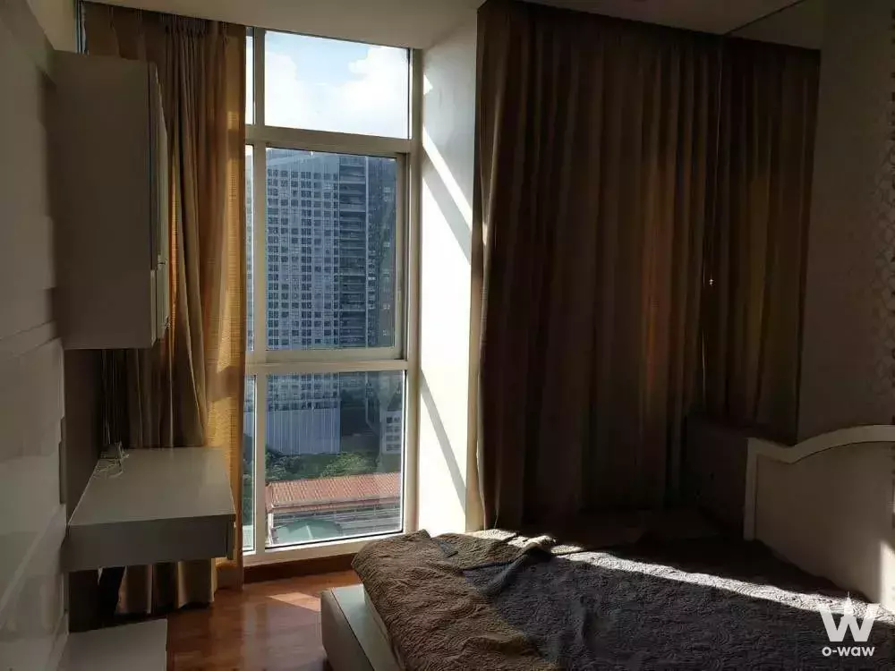 Bright bedroom in a 1-bed condo for sale in The Coast Bangkok with queen bed and floor-to-ceiling city view