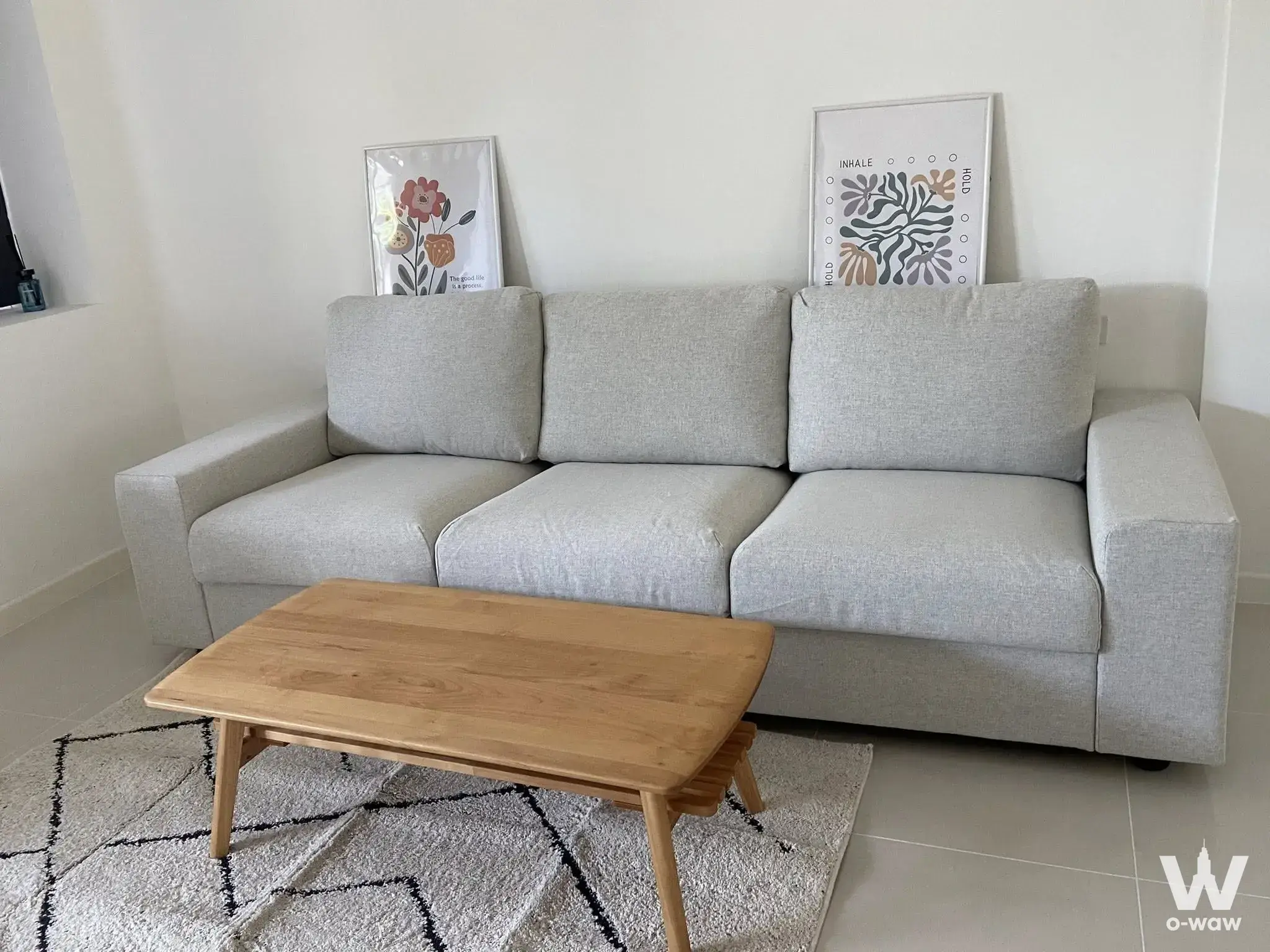 3-bed townhouse for rent in Indy 3 Bangna km.7 featuring a grey sofa, oak coffee table, and botanical wall art