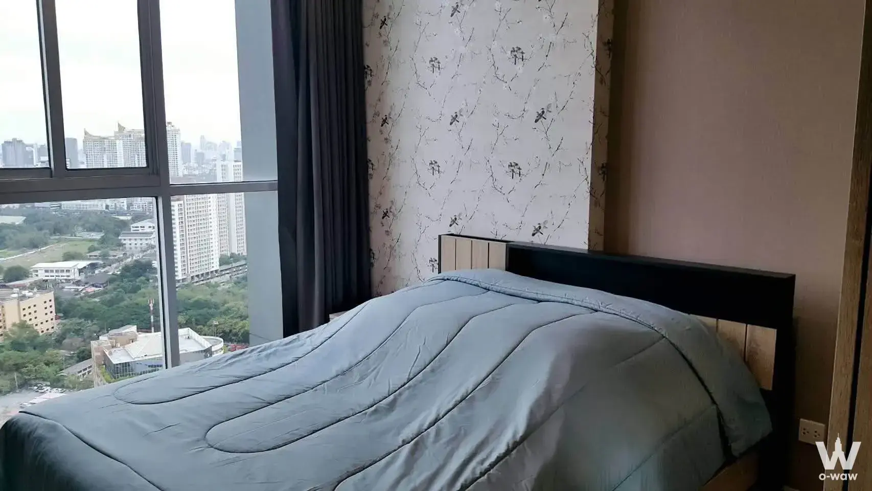 Modern 1-bed bedroom in Noble Revolve Ratchada 2 with floral accent wall and city skyline view