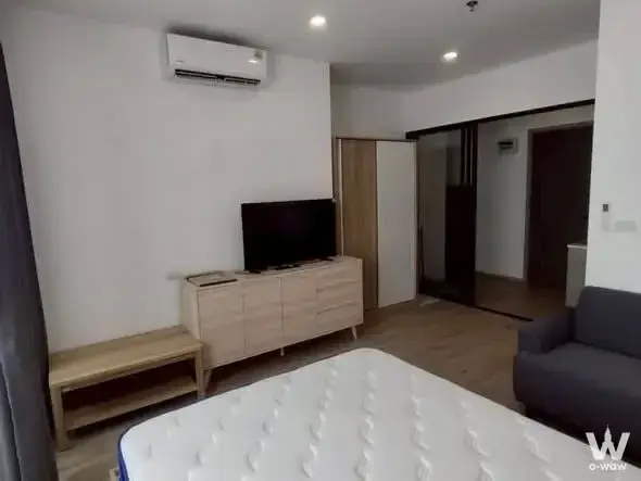 Spacious bedroom in The Rich Rama 9 Srinakarin featuring light wood floors and a flat-screen TV