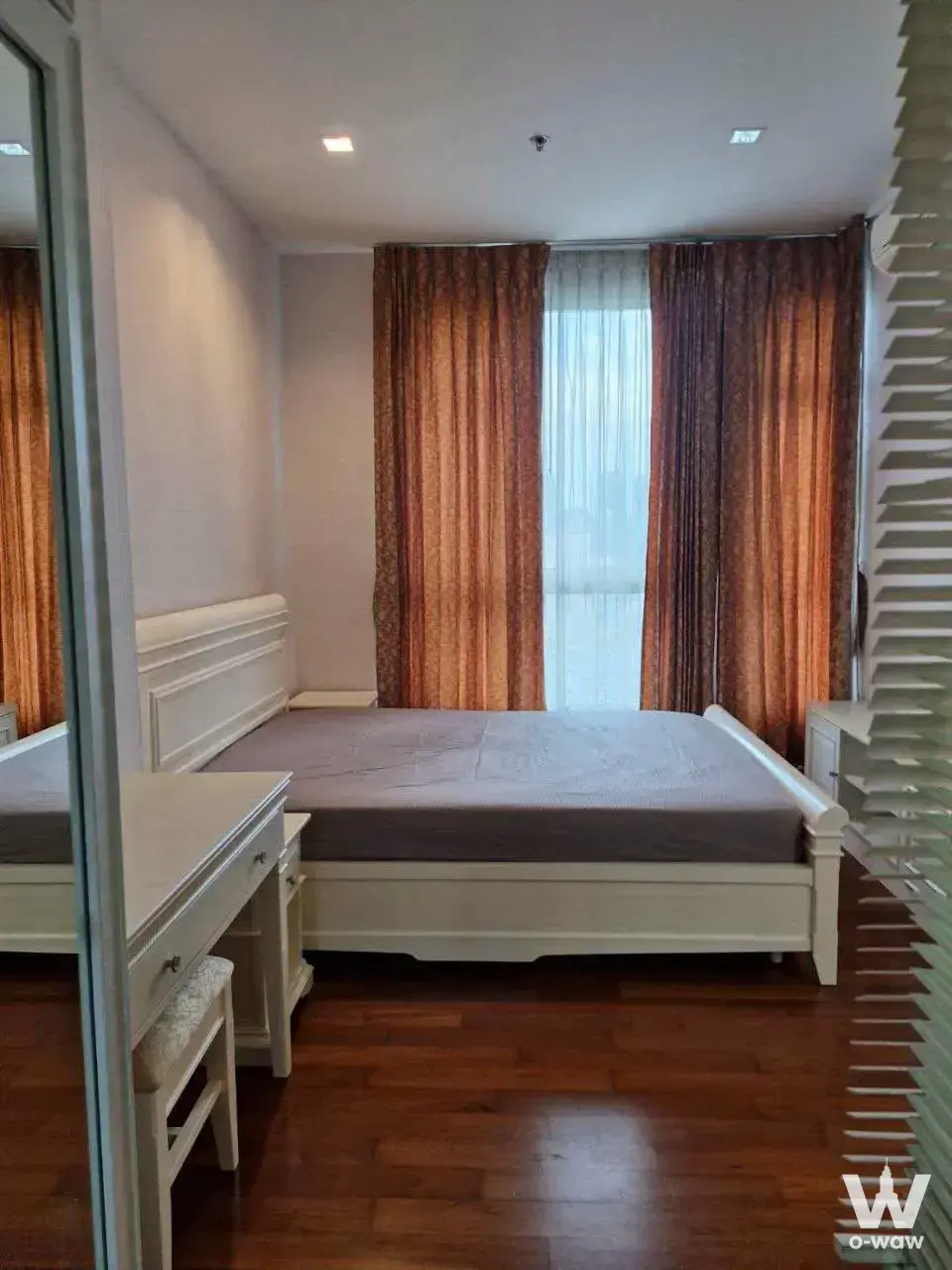 Ivy Sathon 10 1-bed condo bedroom featuring dark hardwood floors and rust-orange drapes