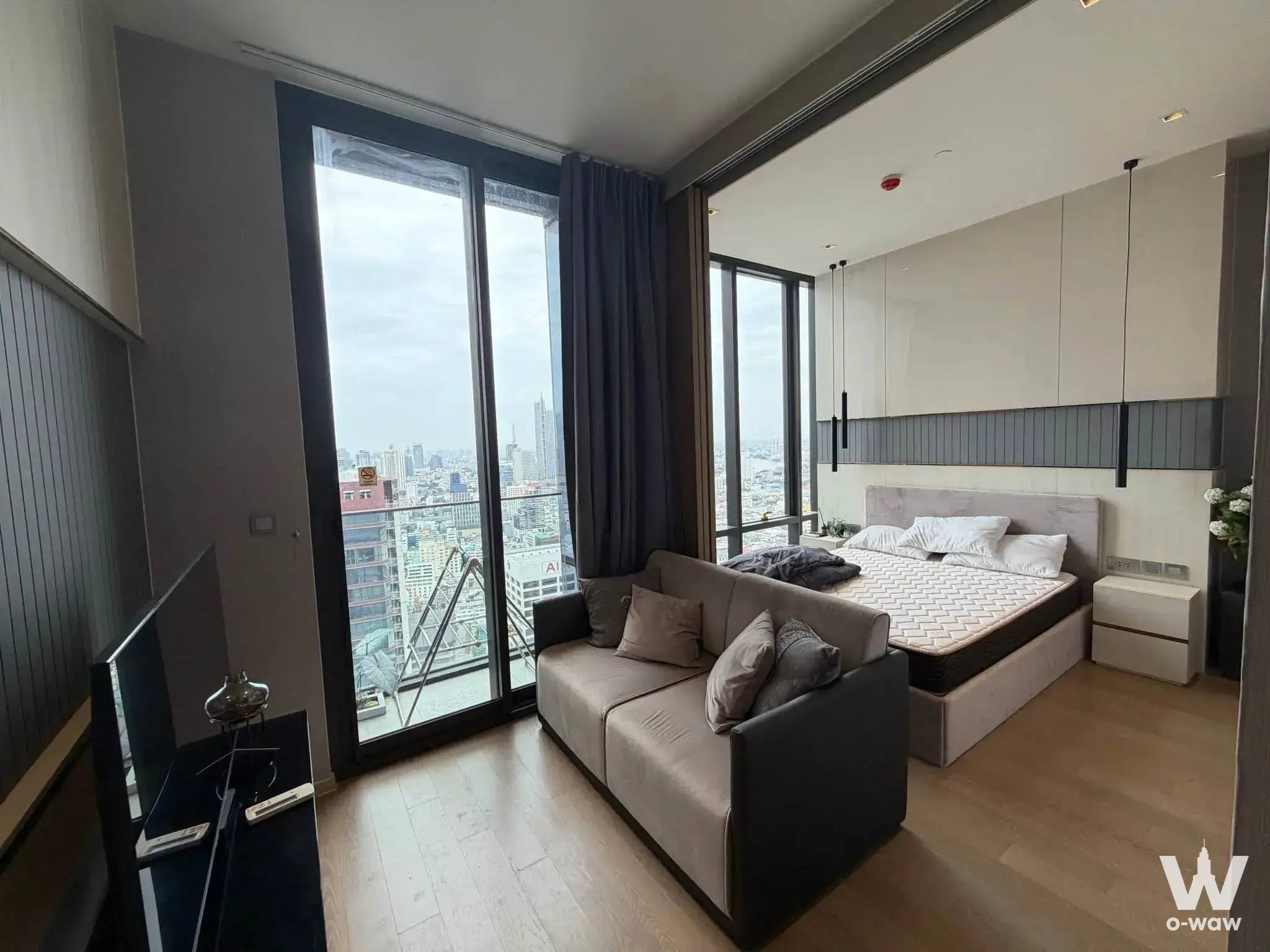 Ashton Silom 1-bed condo living area with city skyline view through floor-to-ceiling glass doors