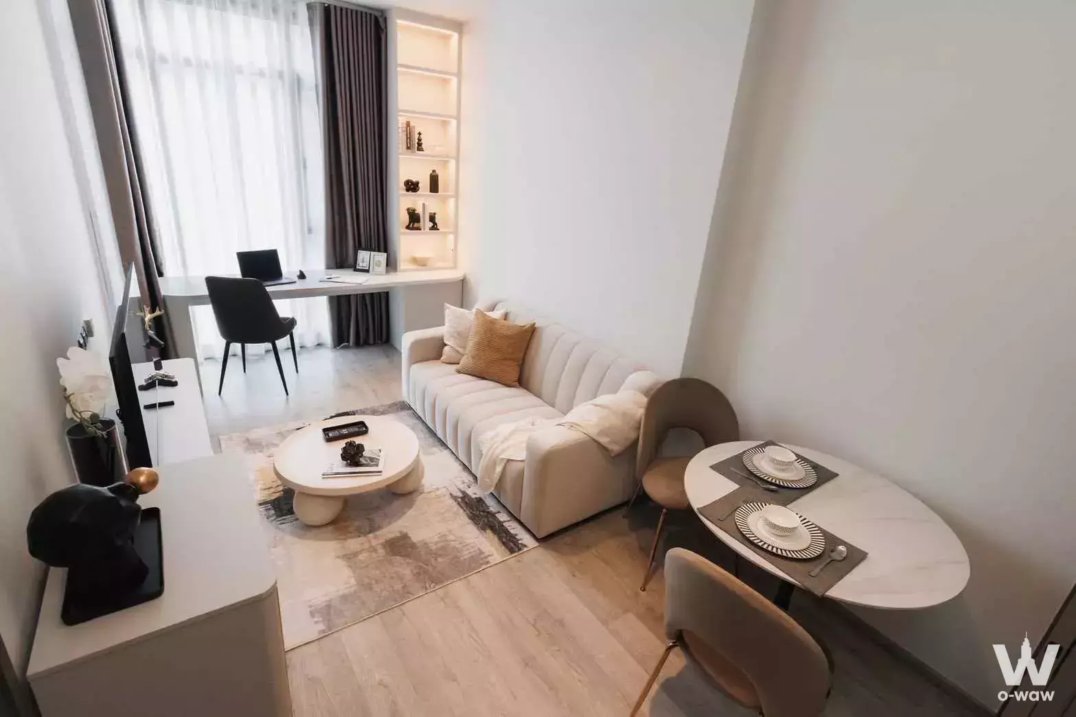Furnished studio at Rhythm Ekkamai Estate with cream tufted sofa, marble dining table, and built-in desk