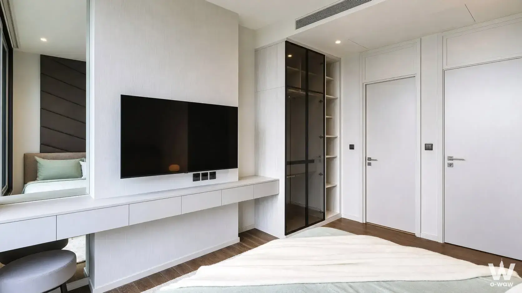 MUNIQ Lang Suan bedroom with dark wood floors, TV, and smoked glass wardrobe
