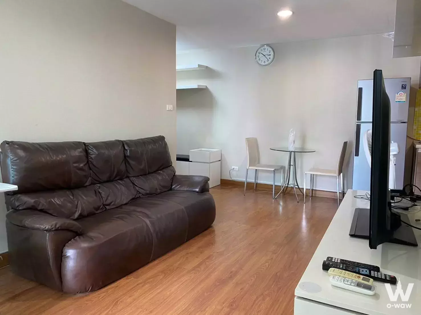 Living room with brown leather sofa and dining set in this Belle Grand Rama 9 1-bed condo for rent