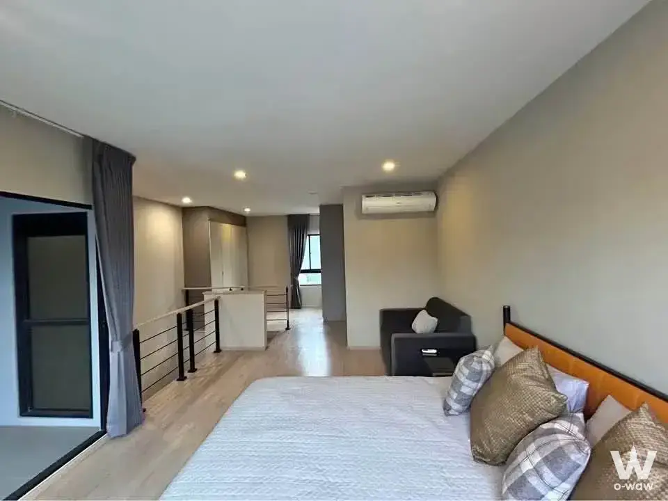 Furnished bedroom in an Arden Phatthanakan townhouse with an orange leather headboard and open-plan layout