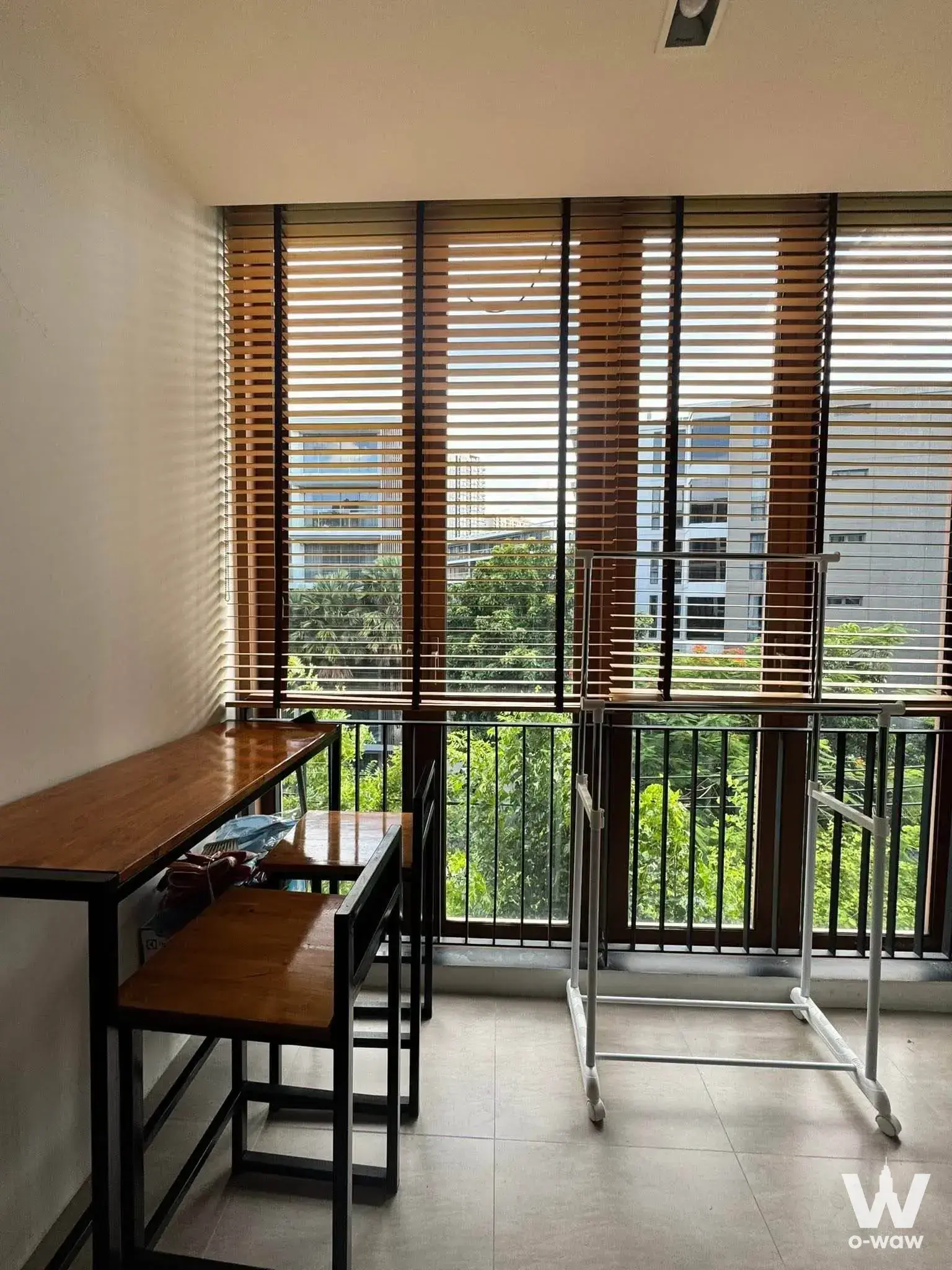Balcony utility area in Mori HAUS condo with wooden desk, drying rack, and tree canopy view