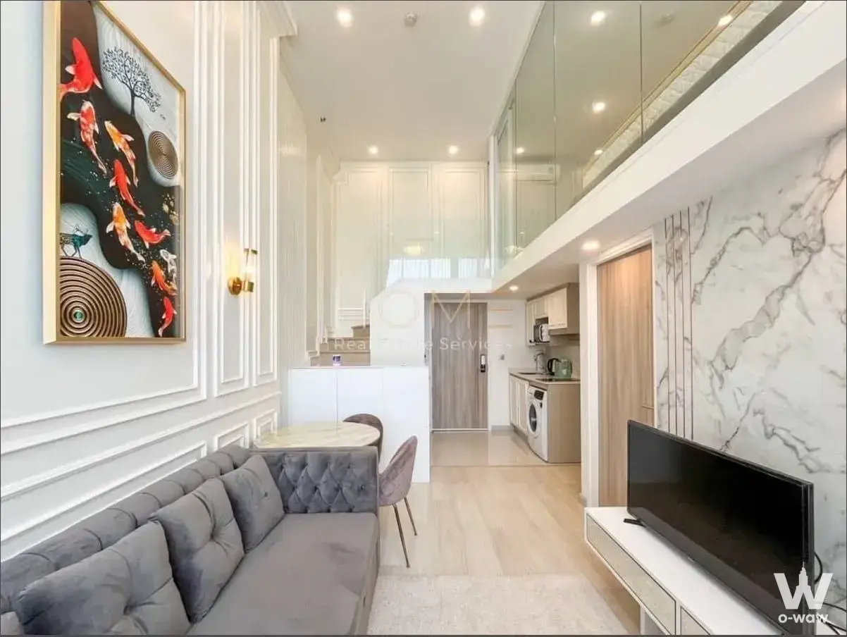 Double-height living area in KnightsBridge Prime Sathon condo featuring grey velvet sofa and marble table