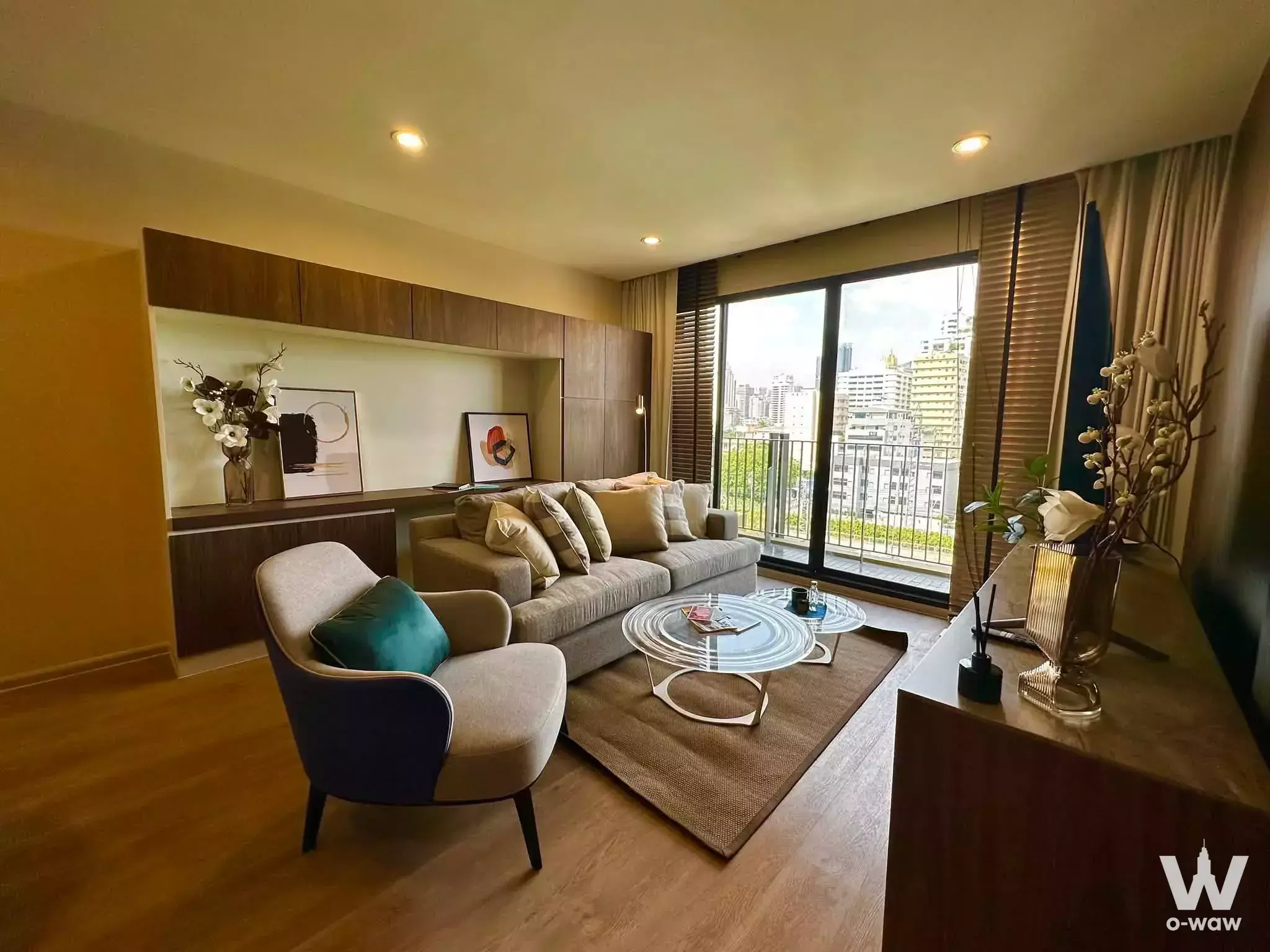 Living room in a 1-bed condo for rent at Noble Above Wireless featuring a beige sofa and floor-to-ceiling balcony doors