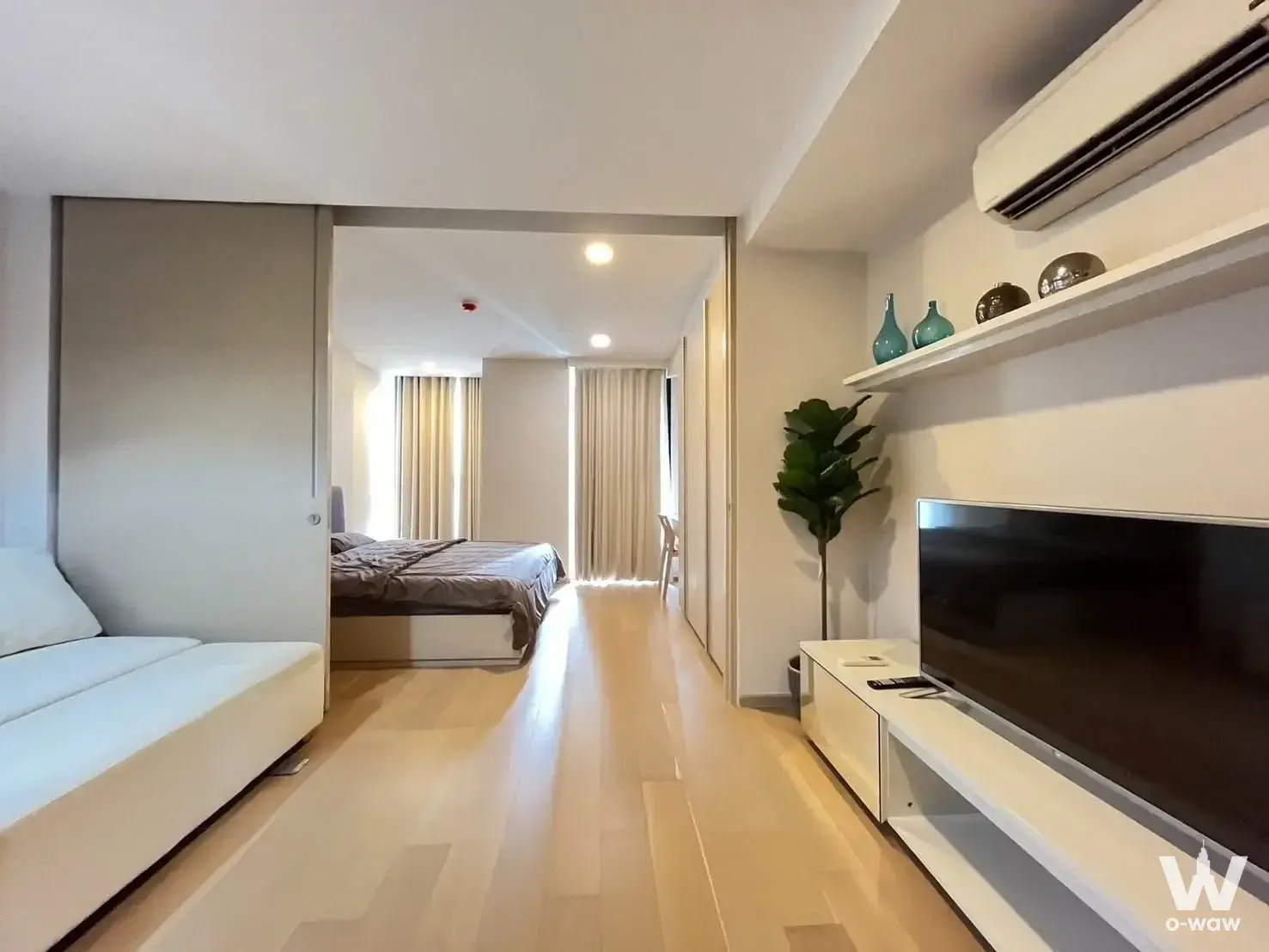 Open studio layout in a Noble BE33 rental showing a living area with TV and view into the bedroom zone