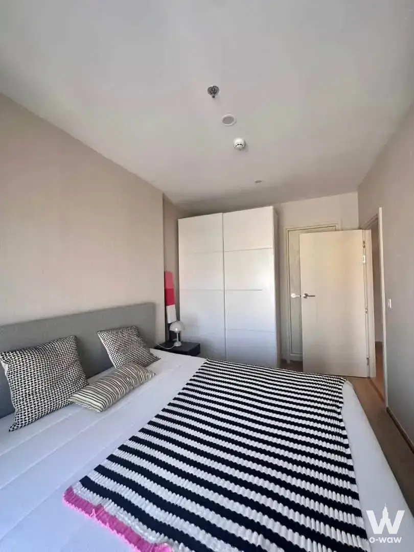 This 1-bed Life Rama 4 Asoke condo has a bedroom with a queen bed and tall white wardrobe