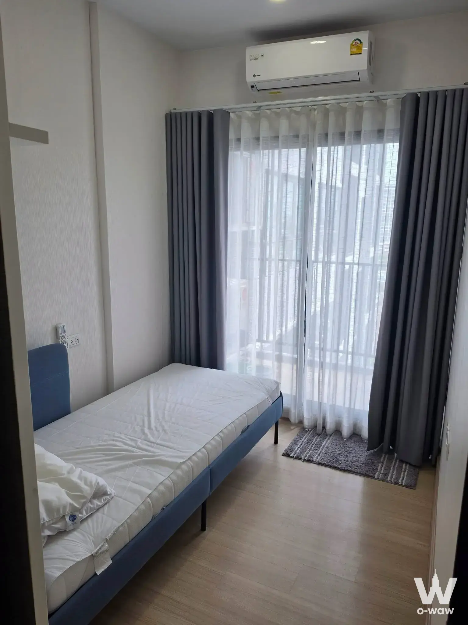 Compact bedroom in a Supalai Loft condo with blue bed and floor-to-ceiling window