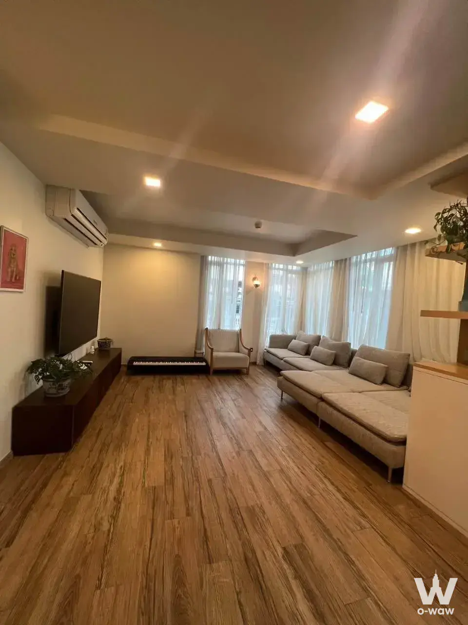 This living room in a 4-bed condo for rent at Maestro 01 Sathorn-Yenakat has an L-shaped sofa and digital piano