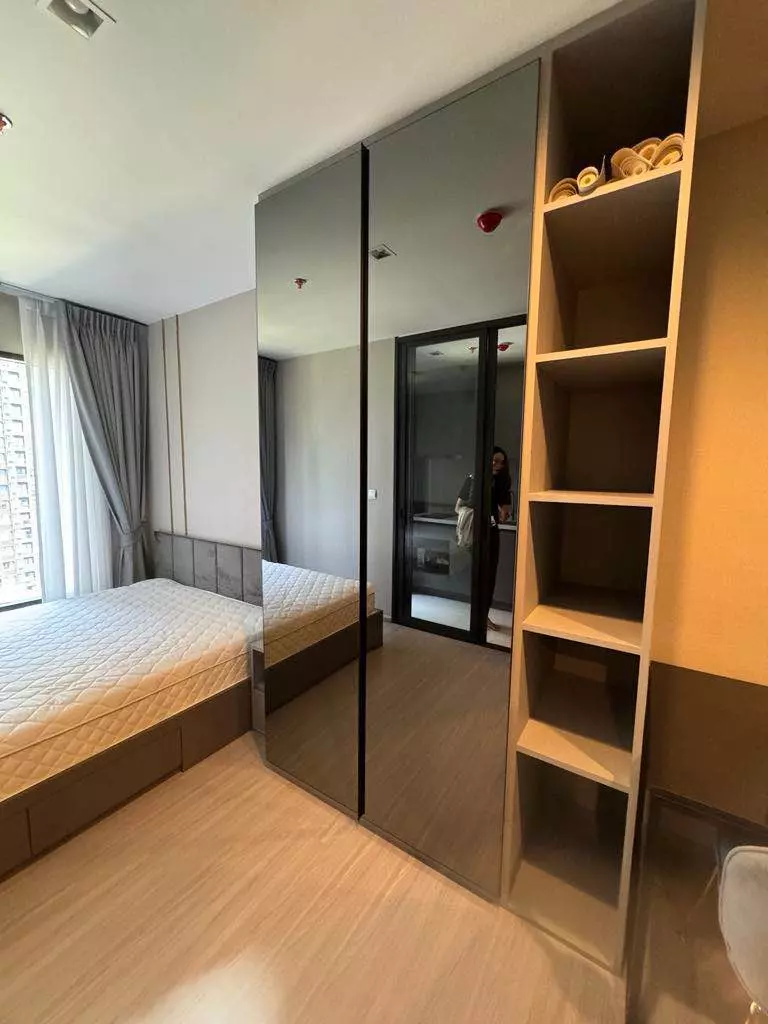 Queen bed in a Life Asoke Hype condo bedroom with floor-to-ceiling mirrored wardrobe doors and light oak flooring