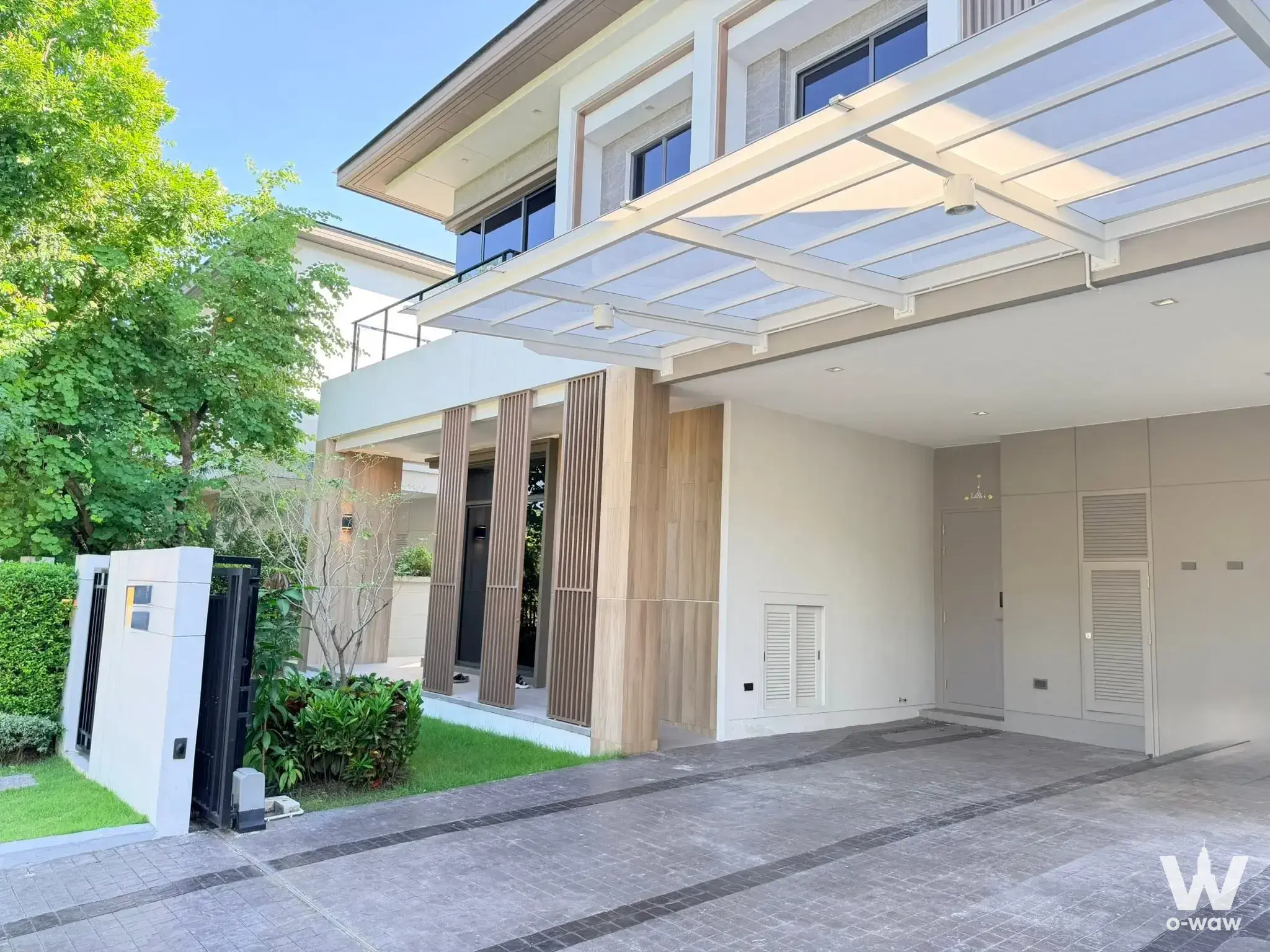 Modern two-story house exterior in Bangkok Boulevard Bangna featuring cream stucco walls and wood slat accents