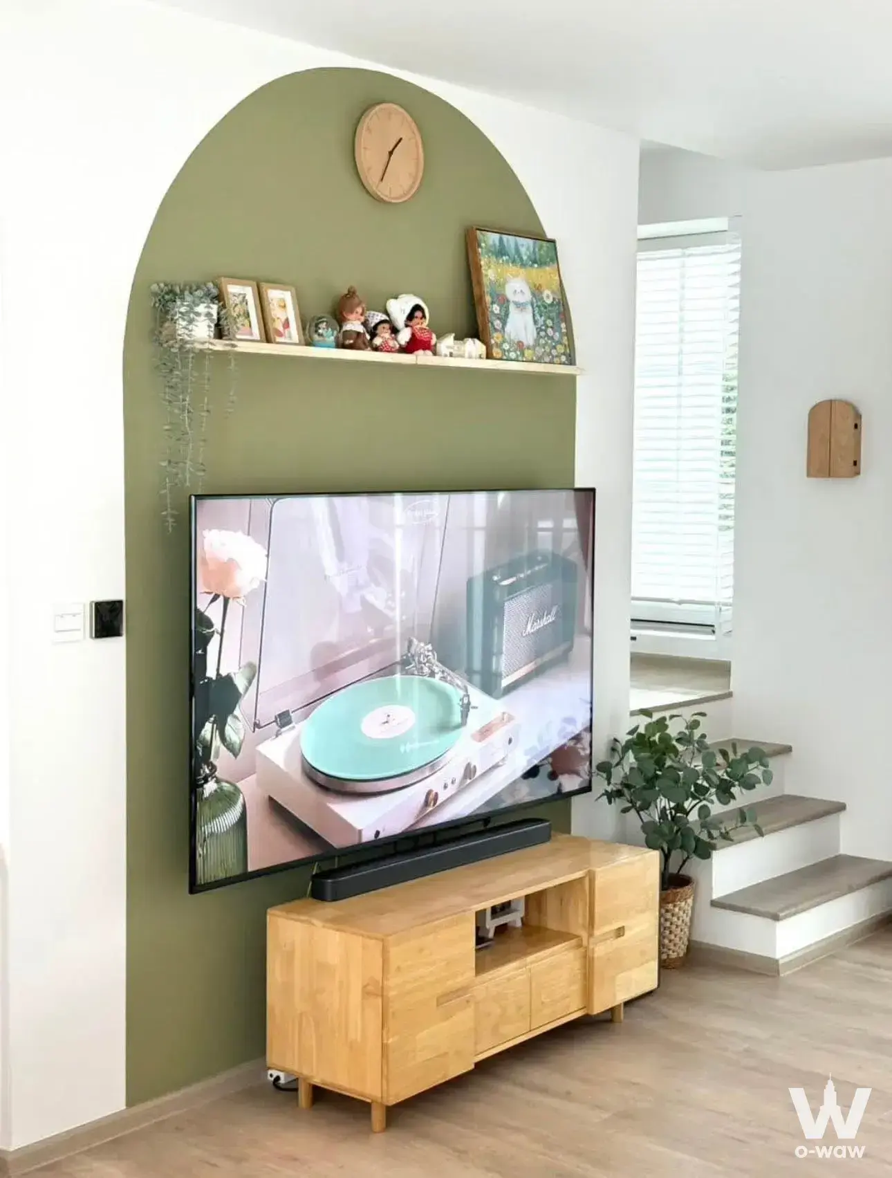 Olive green accent wall and wood console define the living room of this 3-bed condo in Villaggio 3 Srinakarin-Bangna