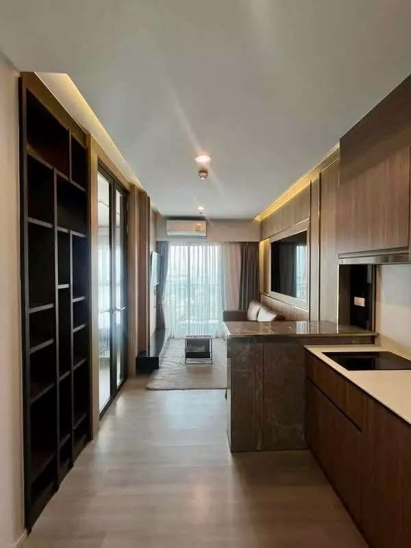 Open-plan living area in The Parkland Charan-Pinklao with dark wood media wall and floor-to-ceiling balcony doors
