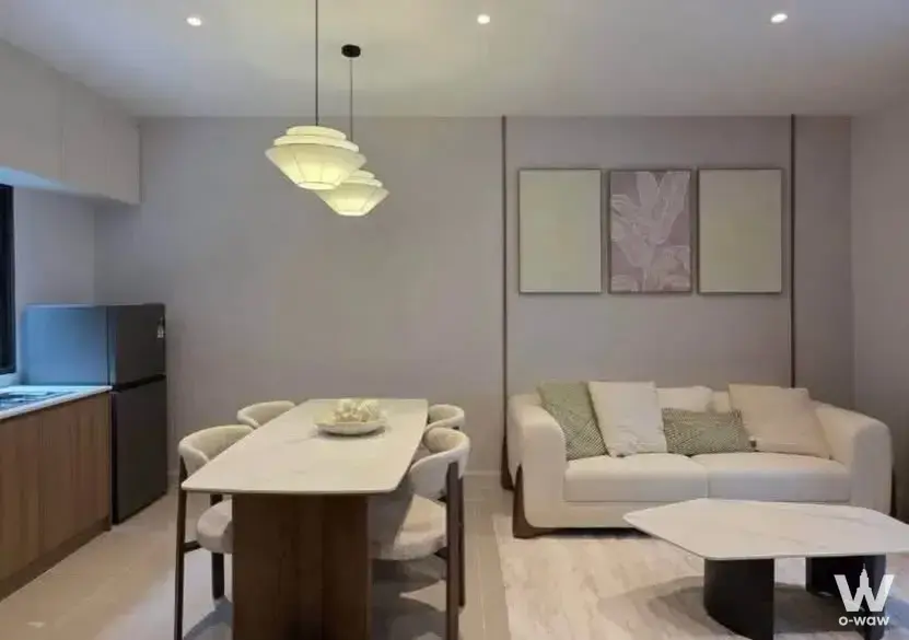 Open-plan living space in a Pleno Sukhumvit-Bangna 2 home with white leather sofa and marble dining table