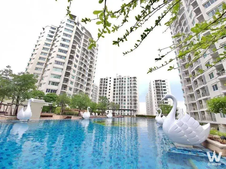 Swan sculptures float on blue mosaic pool water surrounded by high-rise towers at Supalai Wellington II