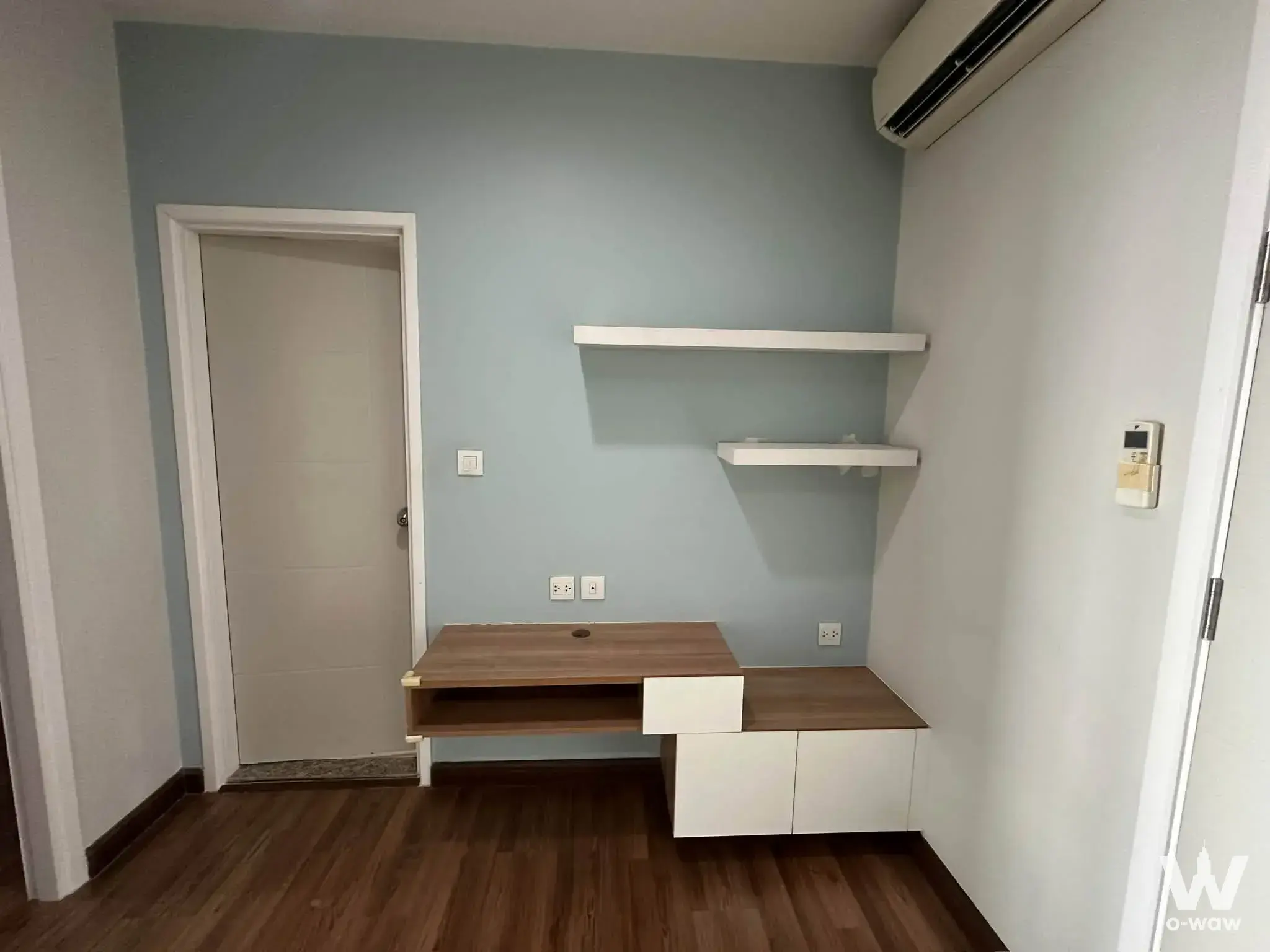 Empty studio room in a 1-bed condo for sale at Centric Tiwanon Station with built-in L-shaped desk and blue-grey wall