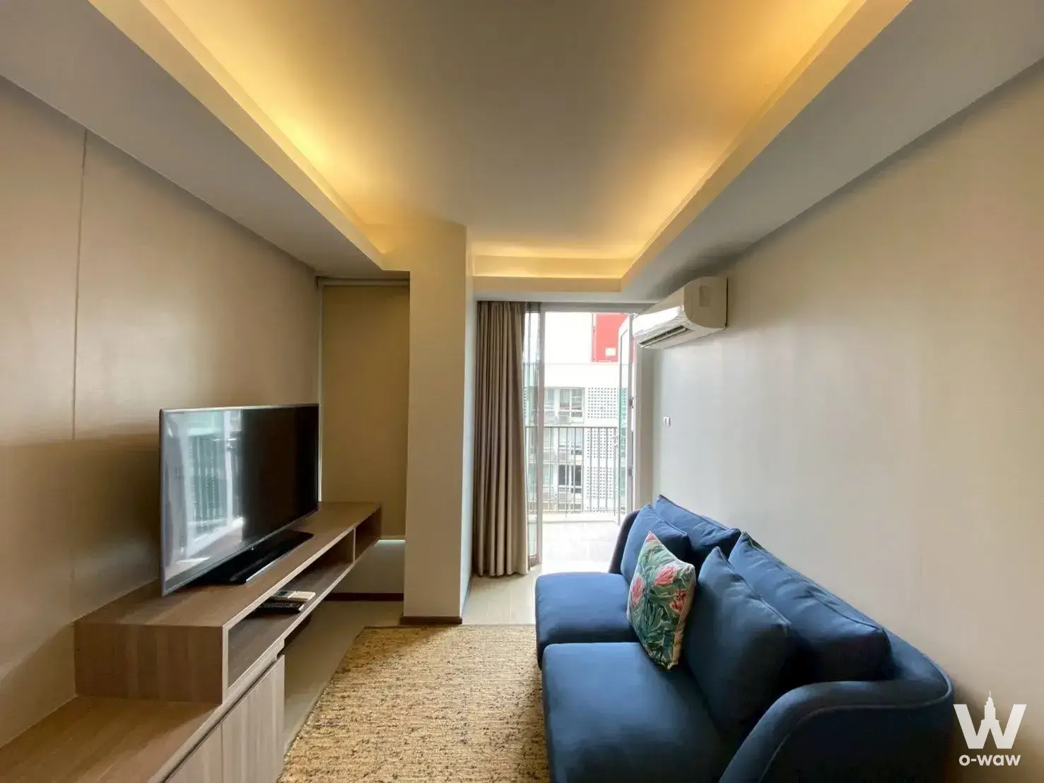 Maitria Residence Rama 9 Bangkok 1-bed condo living room featuring navy sofa and balcony city views