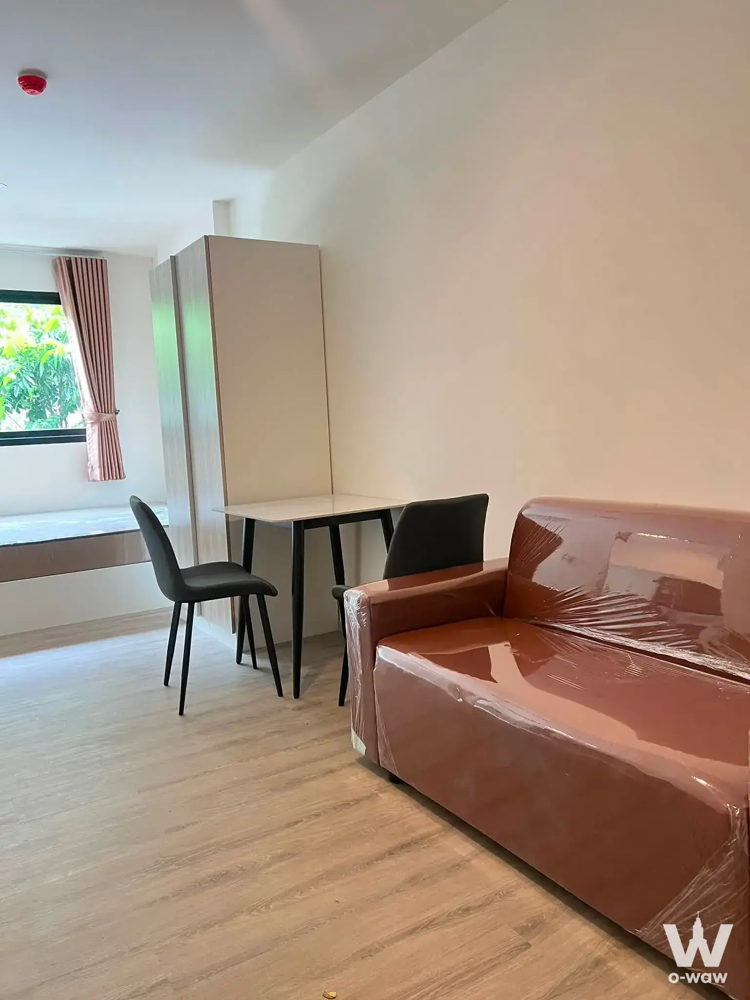Living room in a 1-bed condo for rent at The Origin Bangkae with brown leather sofa still wrapped in protective plastic film