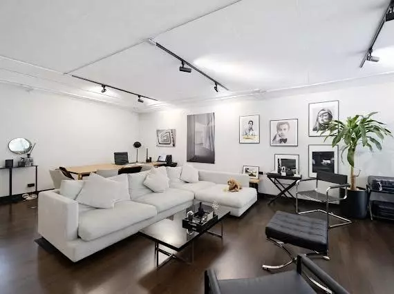 Modern loft living room in President Park with white sectional sofa, black accents, and gallery wall portraits
