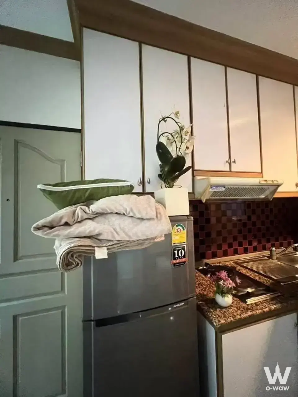 Compact kitchen in a Pathum Wan condo with granite counters and dark red mosaic backsplash