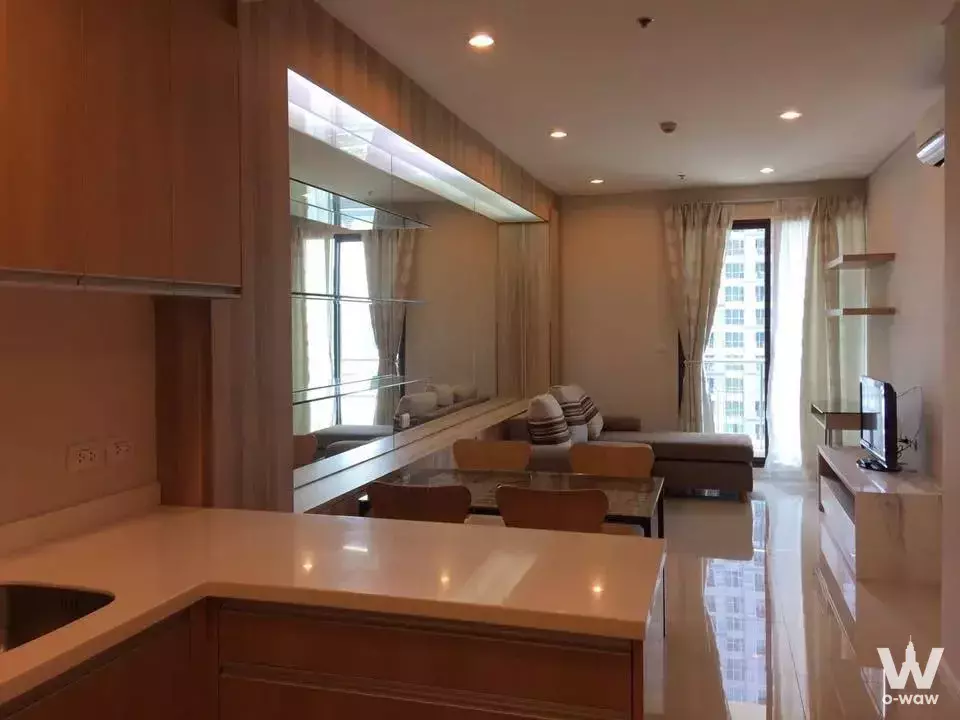 Open-plan 1-bed condo in Villa Asoke with grey sectional sofa and light-wood kitchen cabinets