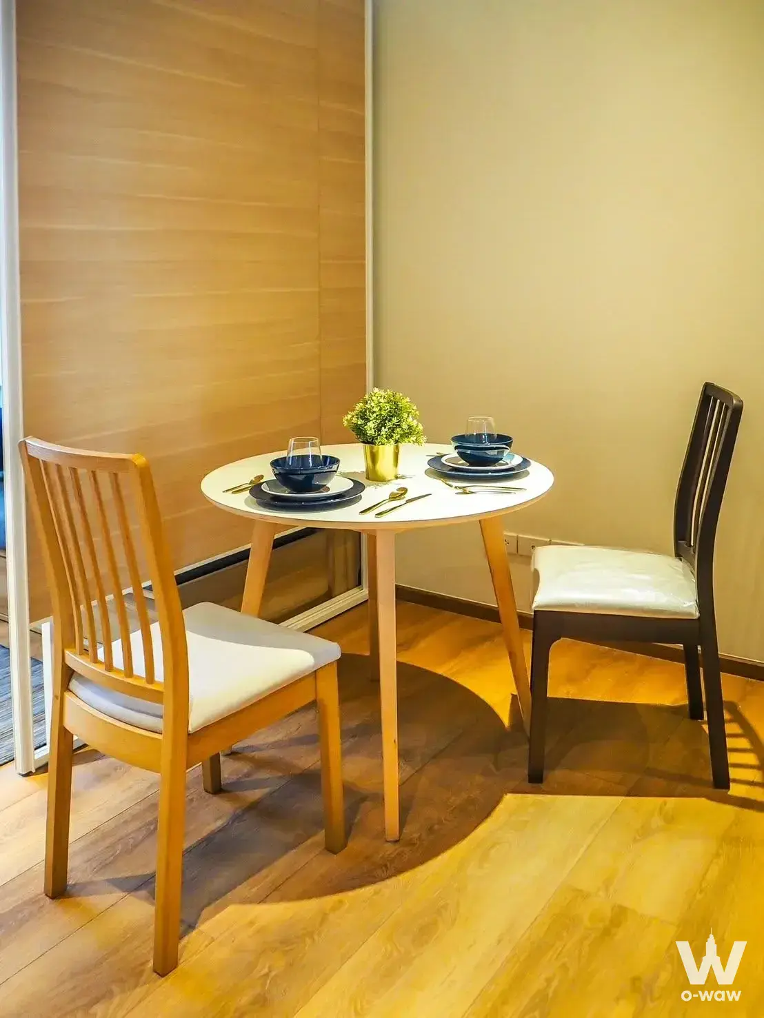 Compact dining nook in a Park Origin Phrom Phong condo with round table, mismatched chairs, and warm ambient lighting