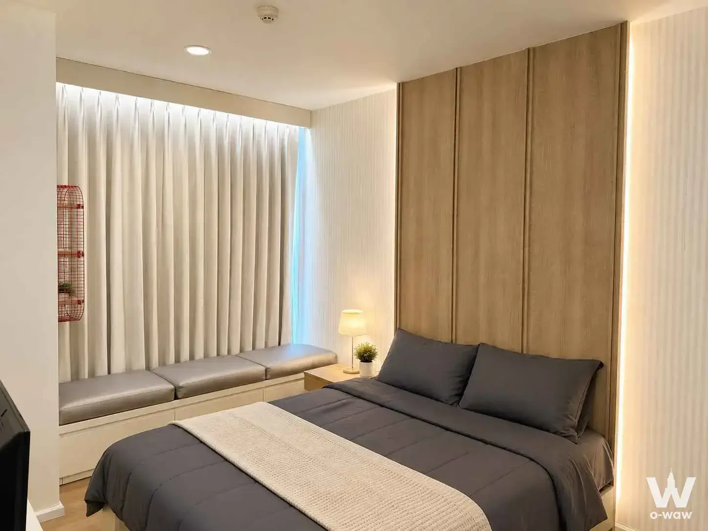 Queen bed with grey duvet and wood headboard in this 1-bed condo for rent at Rhythm Sukhumvit 42