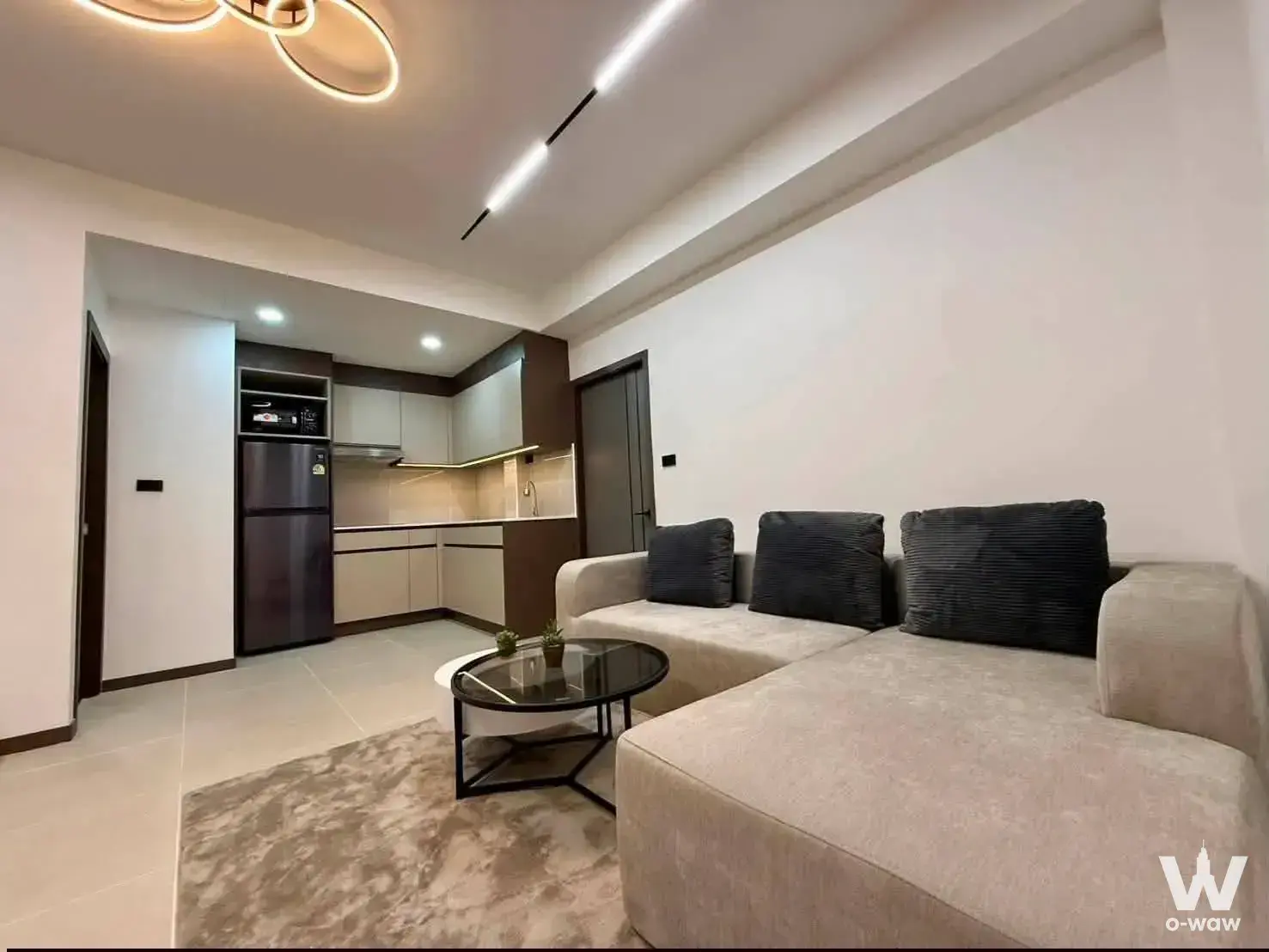 Open-plan living room in a 2-bed Majestic Jomtien condo with beige sectional sofa and modern ring chandelier
