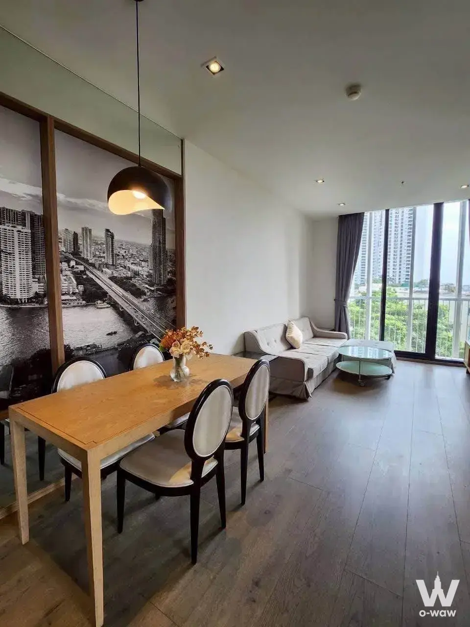 Dining space in a Park Origin Phrom Phong 2-bed condo with oak table, black pendant light, and floor-to-ceiling balcony doors