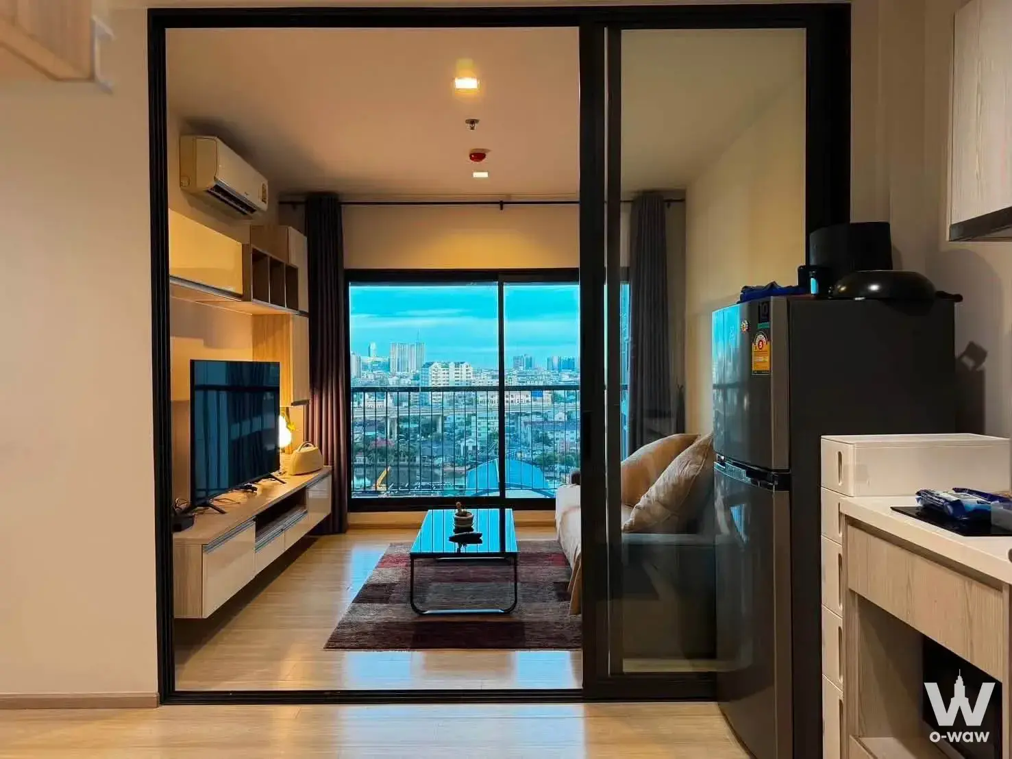 Living room in a 1-bed rental at Life Sukhumvit 48 featuring a beige sofa and floor-to-ceiling city views