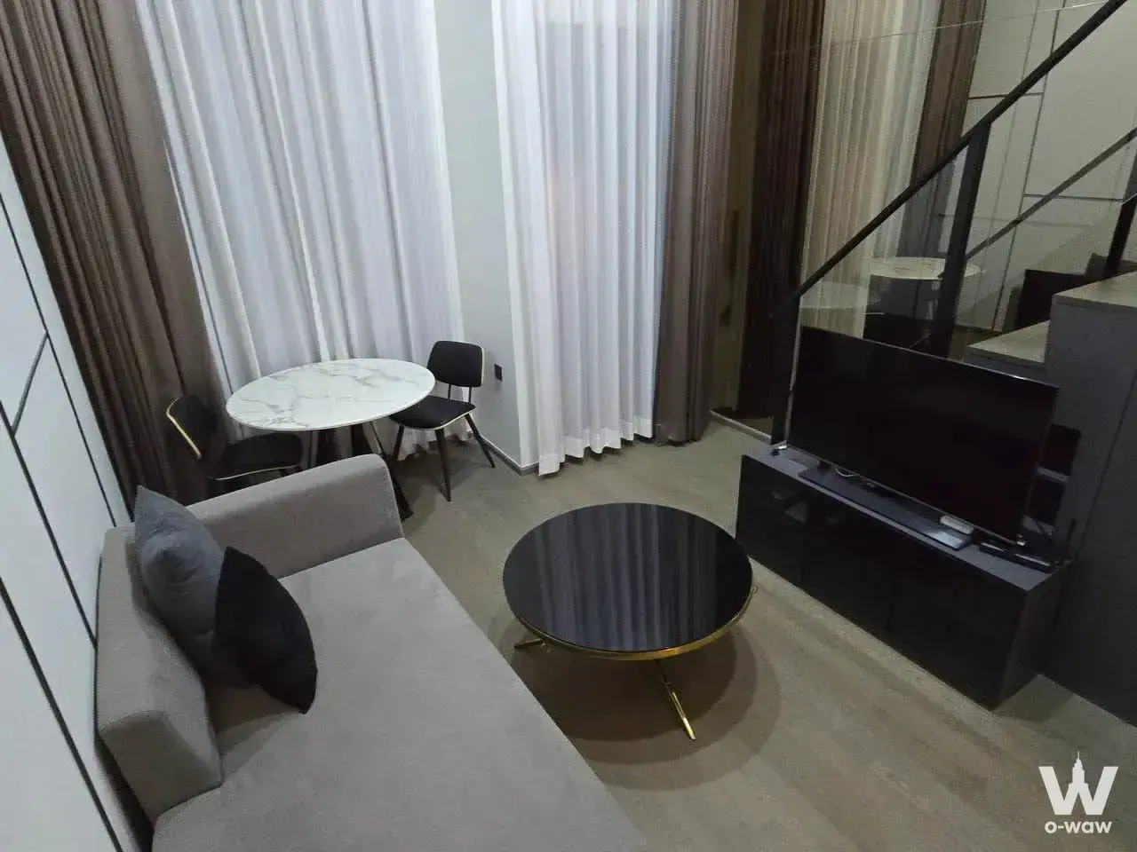 Modern loft living room in a 1-bed condo for rent at Park Origin Chula-Samyan featuring grey sofa and floor-to-ceiling