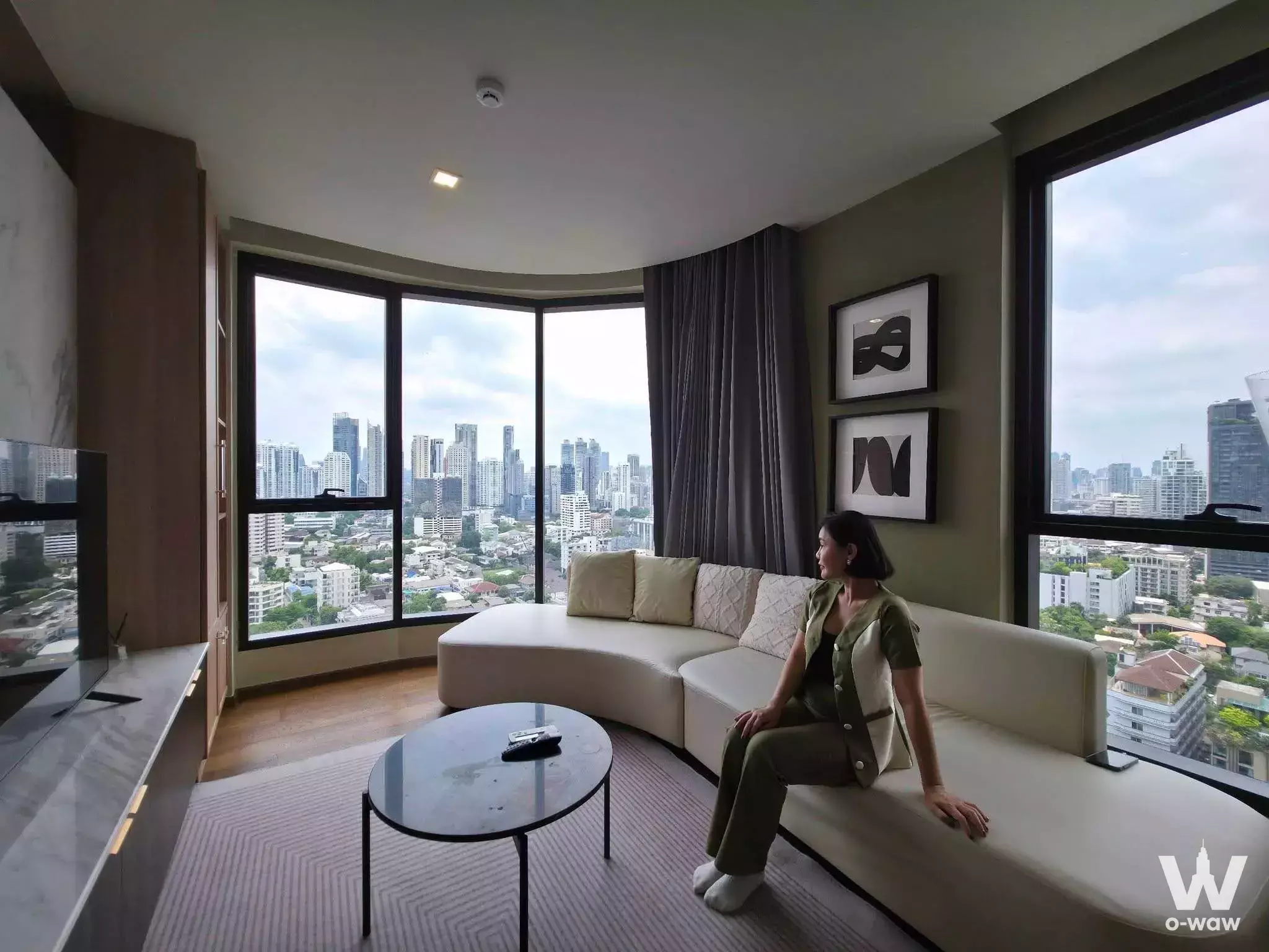 Living room in a 2-bed condo for rent at Ideo Q Sukhumvit 36 with curved leather sofa and floor-to-ceiling city views