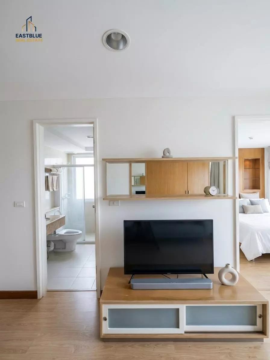 Bright living room in The Bangkok Narathiwat condo for sale with light oak floors, mirrored shelving, and city views
