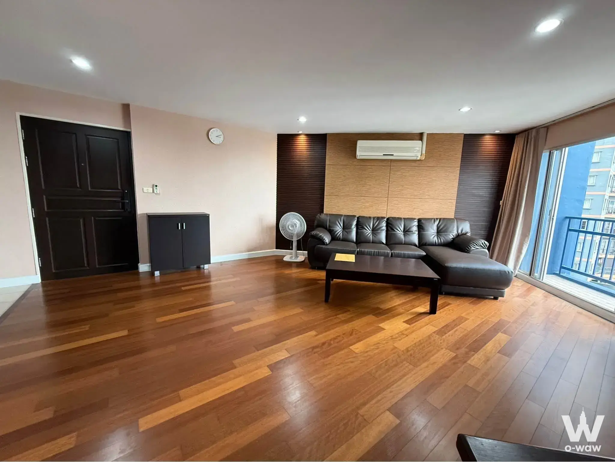 Belle Park Residence 2-bed condo living room with dark brown leather sectional and light oak slat accent wall