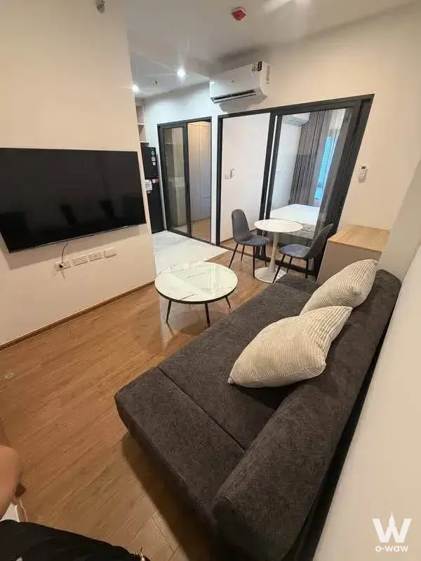 Modern 1-bed condo living room in The Livin Ramkhamhaeng with dark-grey sofa and marble coffee table