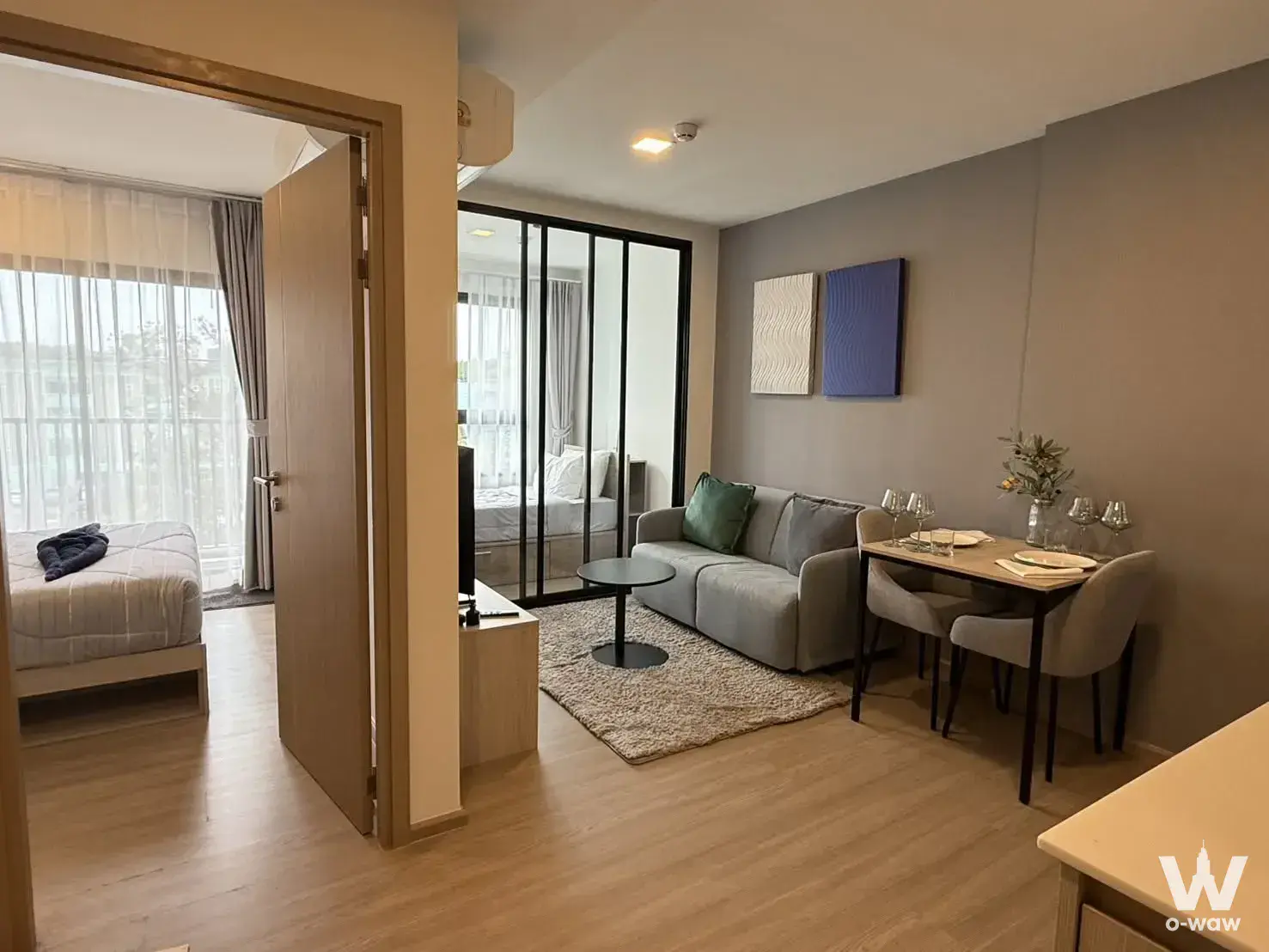 Furnished Phuket studio condo with grey sofa, dining area, and separate bedroom at The Base Bukit Phuket