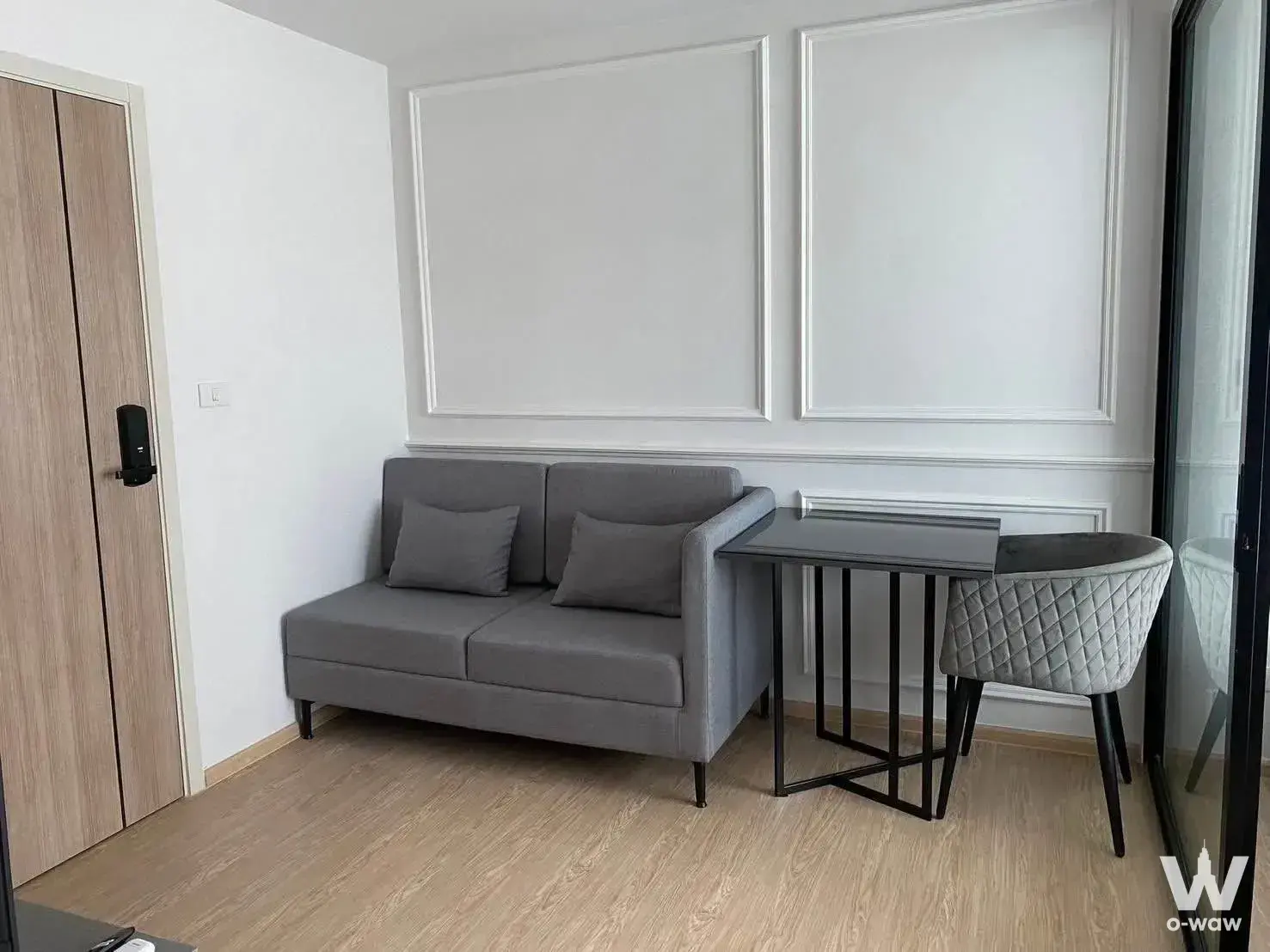 Living area in The Excel Ratchada 18 rental with grey sofa, oak wardrobe, and floor-to-ceiling sliding doors