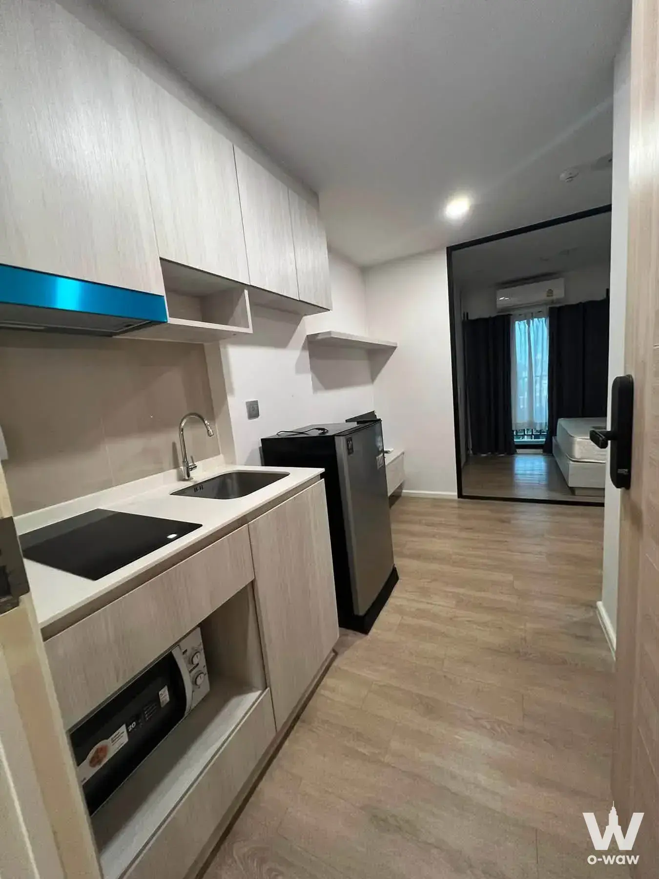 Compact kitchenette with light wood cabinets and a black induction cooktop in this Ivory Ratchada 32 rental