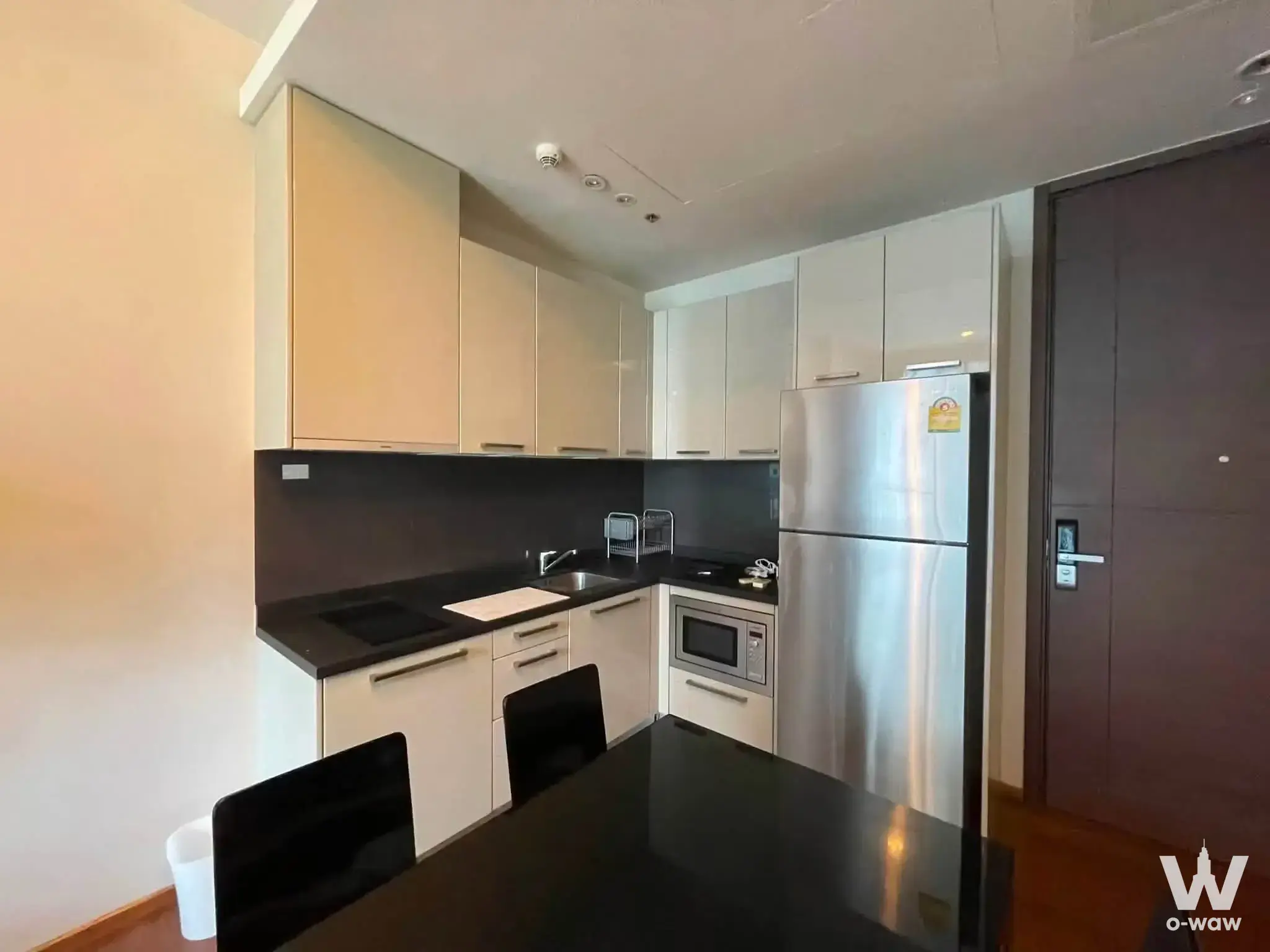 Kitchen in a Quattro by Sansiri 1-bed condo featuring L-shaped cream cabinets and black granite countertops