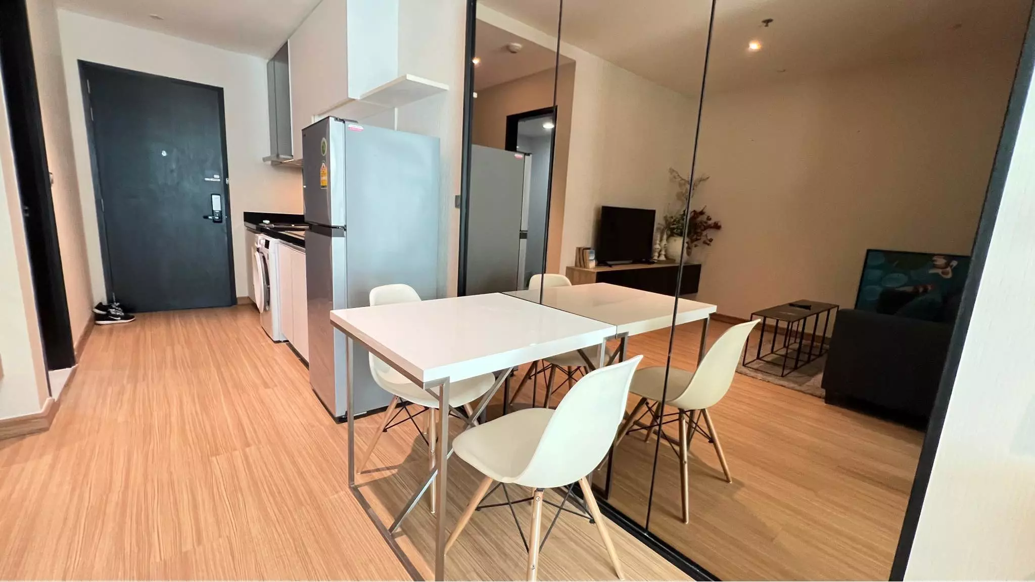 Minimalist studio for rent in Sky Walk Residences with grey sofa, white dining set, and full-length mirror