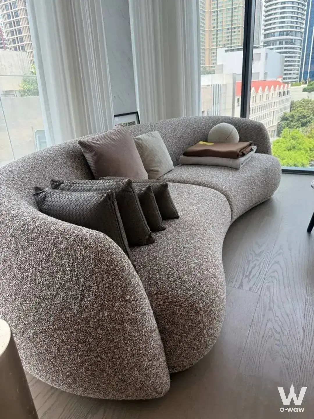 Modern 2-bed condo for sale in SCOPE Langsuan with textured grey sectional sofa and floor-to-ceiling windows
